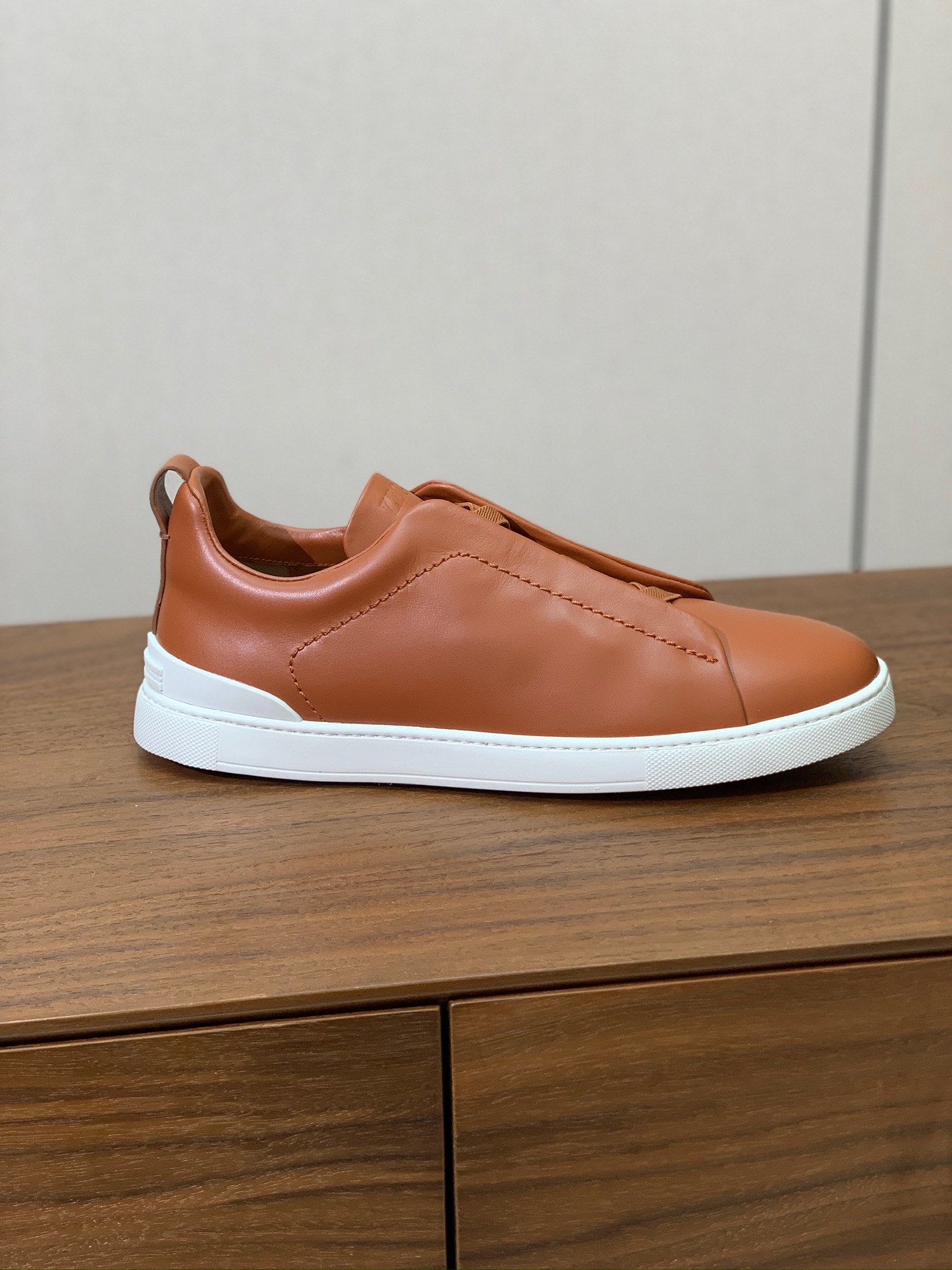 【Zegna】光面牛皮一脚蹬休闲鞋。饰有标志性三重交叉松紧细节，灵感源于三重手缝线迹造型，彰显了杰尼亚的