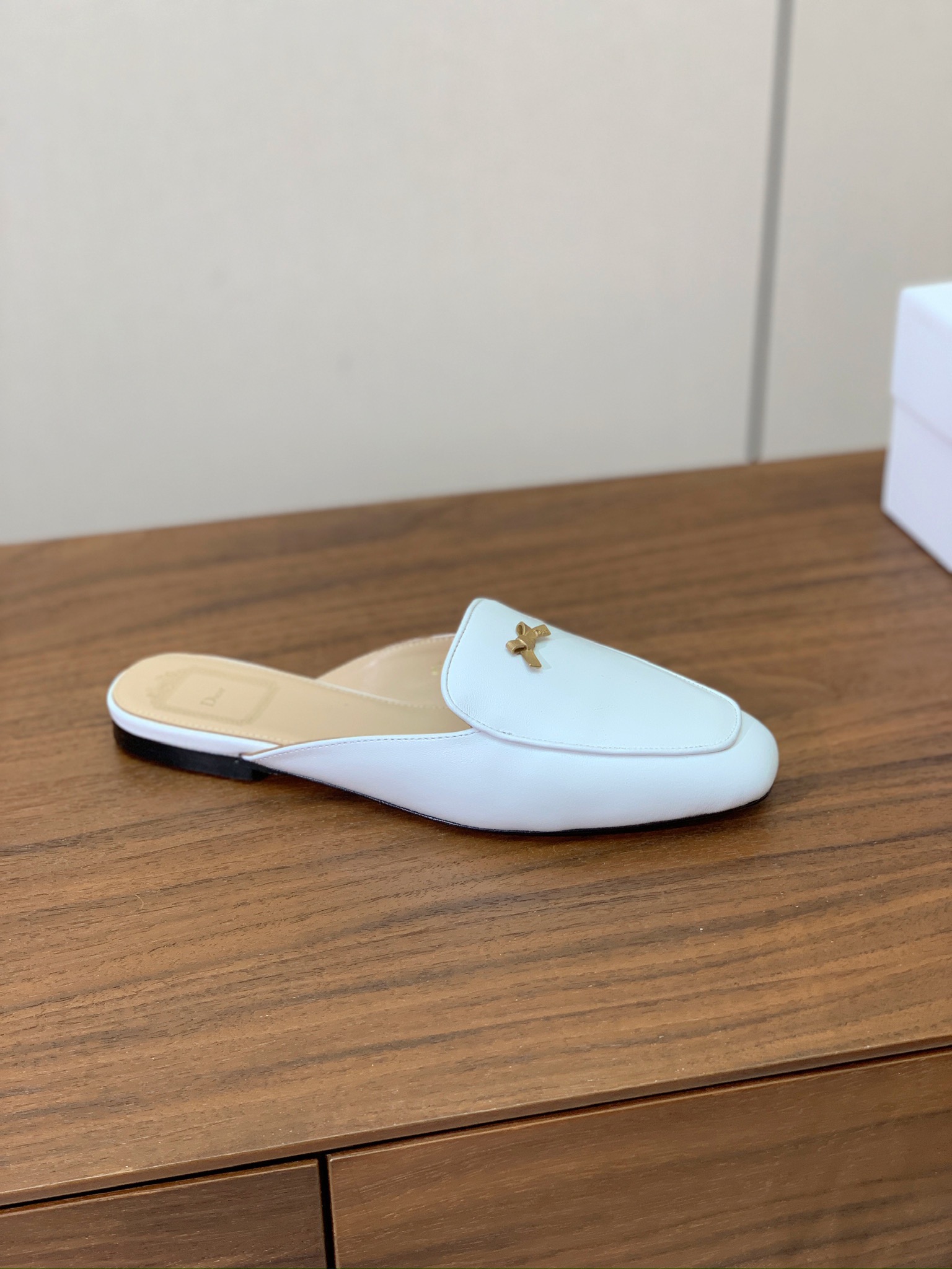 【D*or】蝴蝶结包头拖。修长方形鞋头和精致的金色饰面金属蝴蝶结装饰。采用绒面羊皮革精心制作，彰显舒适穿