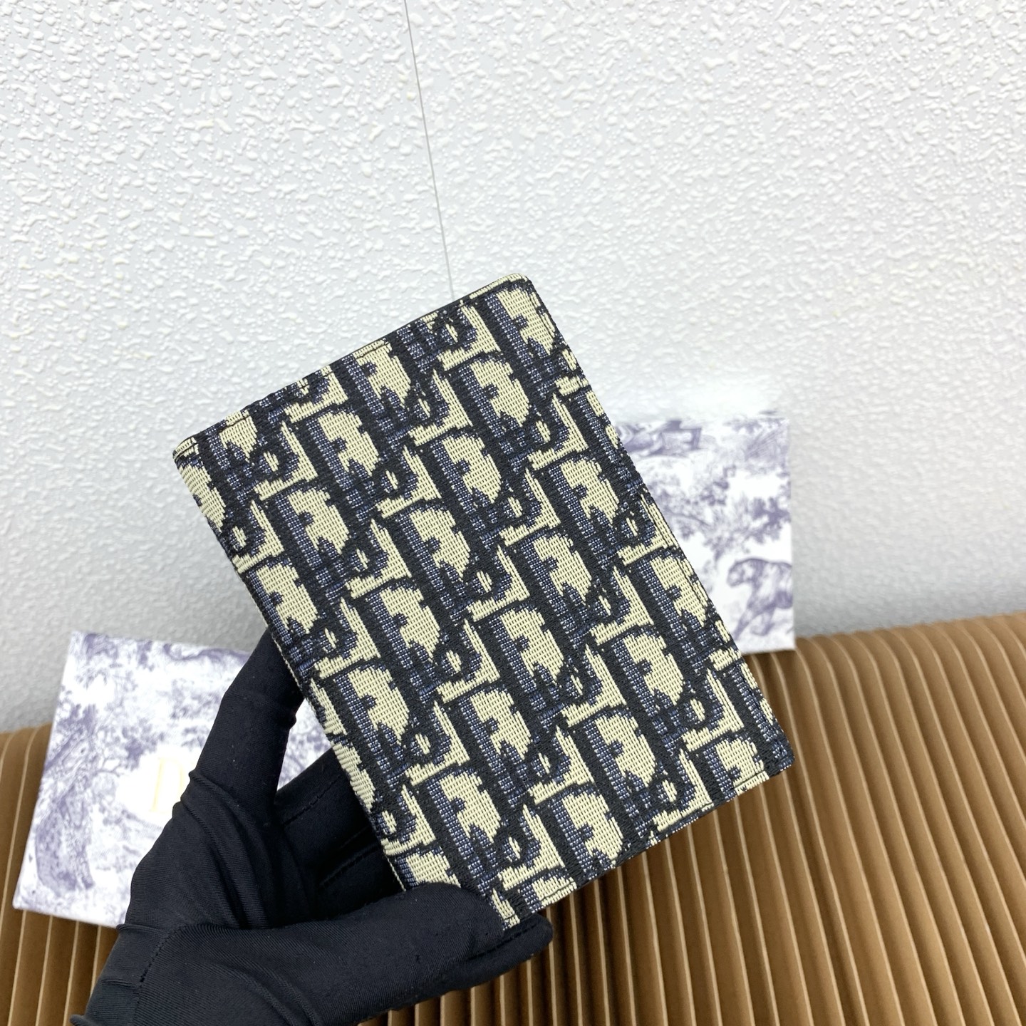 这款护照套是实用典雅的配饰。采用米色和黑色 Dior Oblique 缇花制作，正面缀以 Dior 标志
