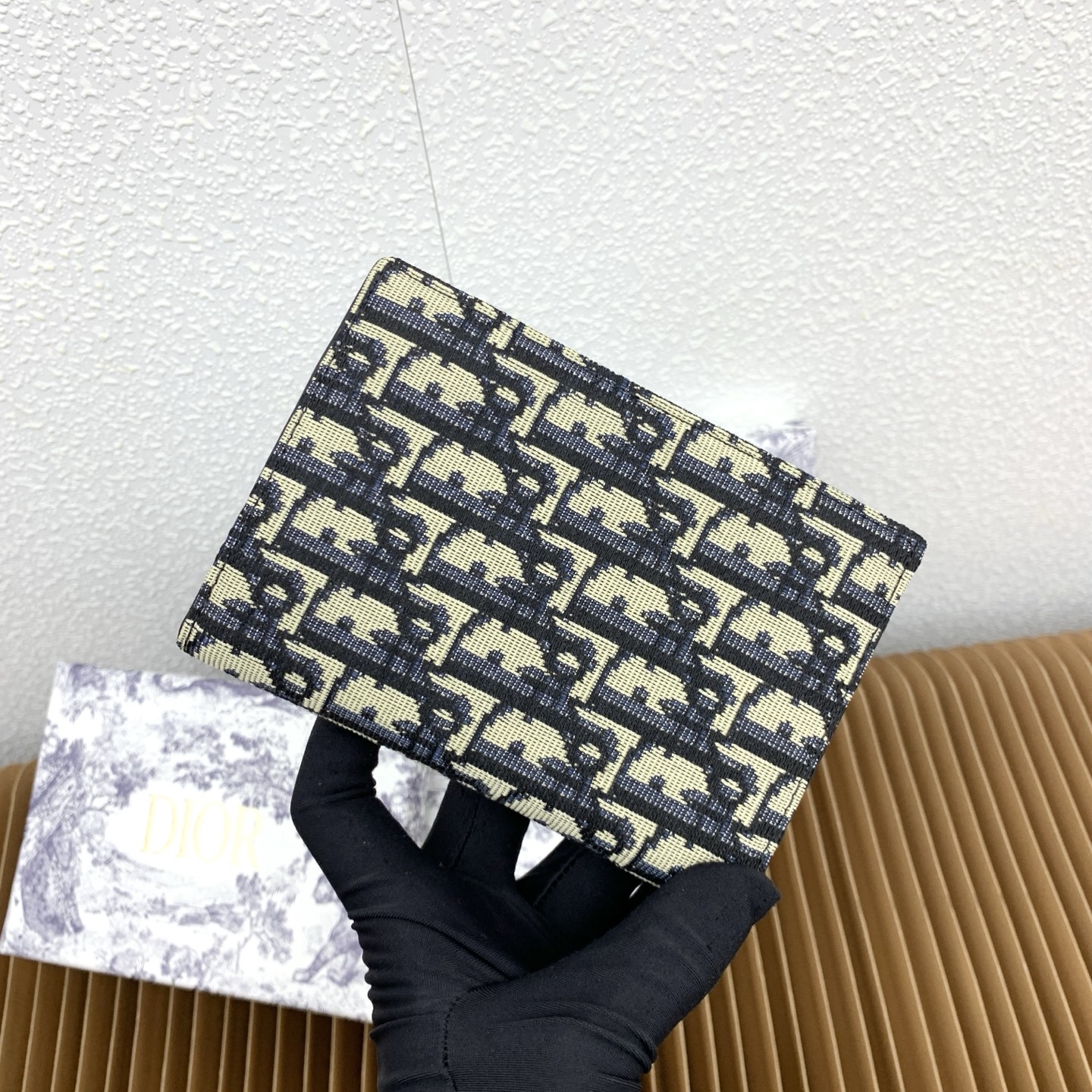 这款护照套是实用典雅的配饰。采用米色和黑色 Dior Oblique 缇花制作，正面缀以 Dior 标志