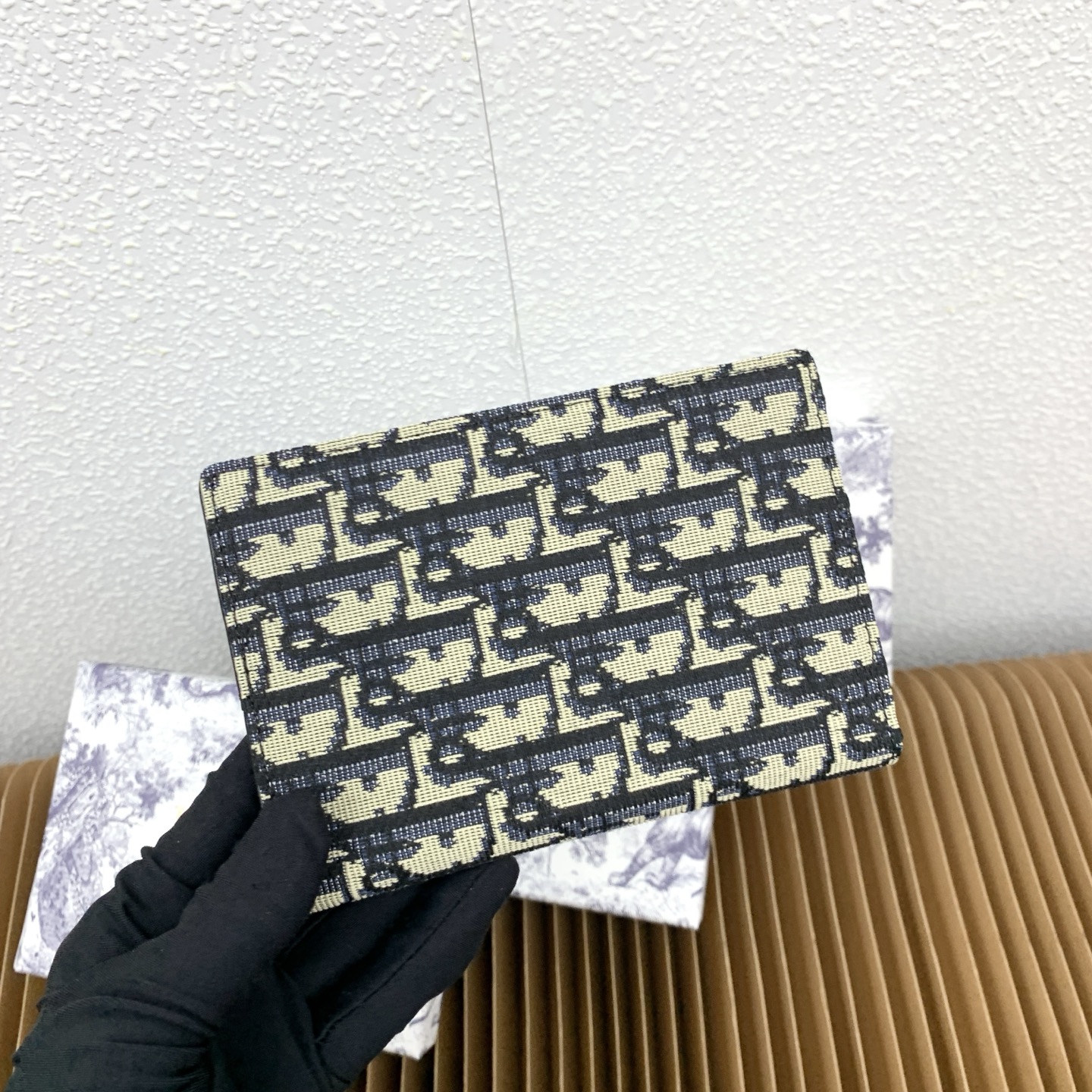 这款护照套是实用典雅的配饰。采用米色和黑色 Dior Oblique 缇花制作，正面缀以 Dior 标志