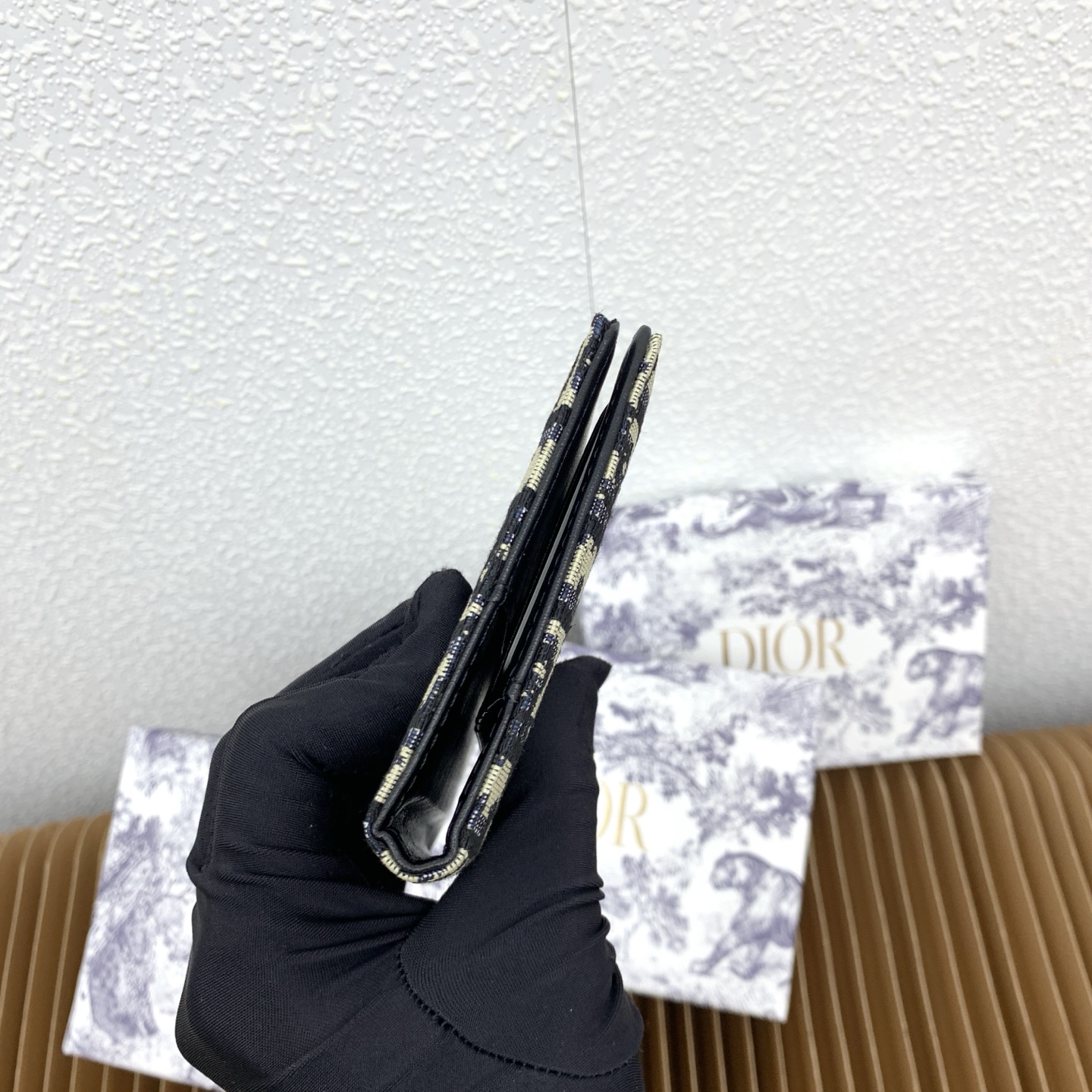 这款护照套是实用典雅的配饰。采用米色和黑色 Dior Oblique 缇花制作，正面缀以 Dior 标志