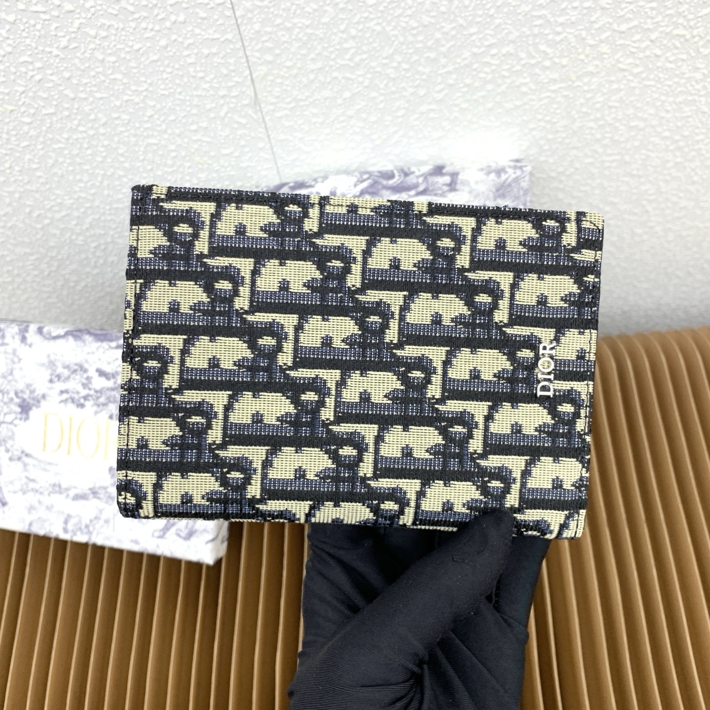 这款护照套是实用典雅的配饰。采用米色和黑色 Dior Oblique 缇花制作，正面缀以 Dior 标志