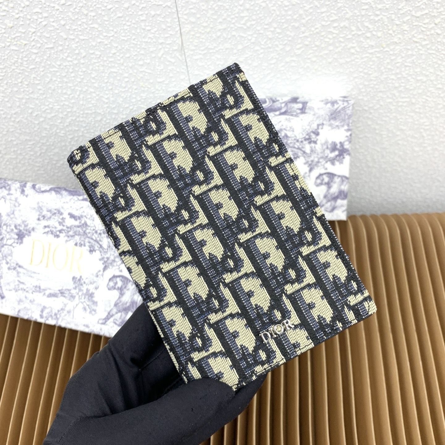 这款护照套是实用典雅的配饰。采用米色和黑色 Dior Oblique 缇花制作，正面缀以 Dior 标志