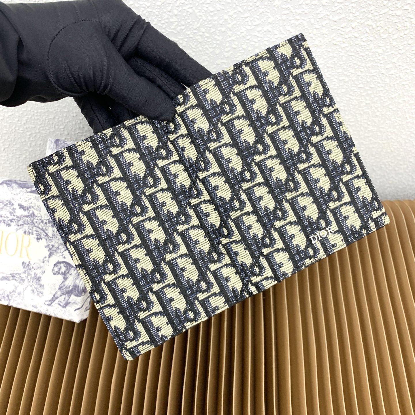 这款护照套是实用典雅的配饰。采用米色和黑色 Dior Oblique 缇花制作，正面缀以 Dior 标志