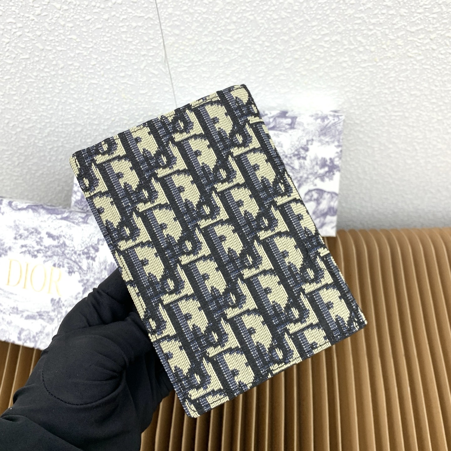 这款护照套是实用典雅的配饰。采用米色和黑色 Dior Oblique 缇花制作，正面缀以 Dior 标志