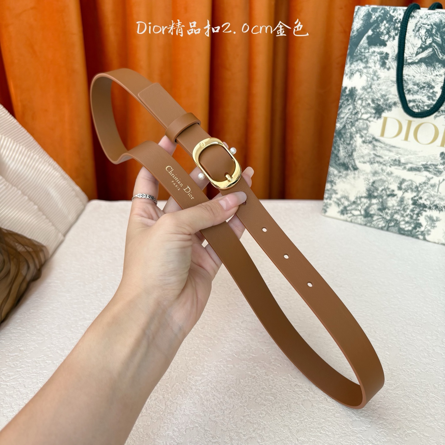 Dior新款腰带采用光滑牛皮材质精心制作，搭配富有光泽的金色饰面金属腰带扣，彰显优雅线条，并镌刻以CD标