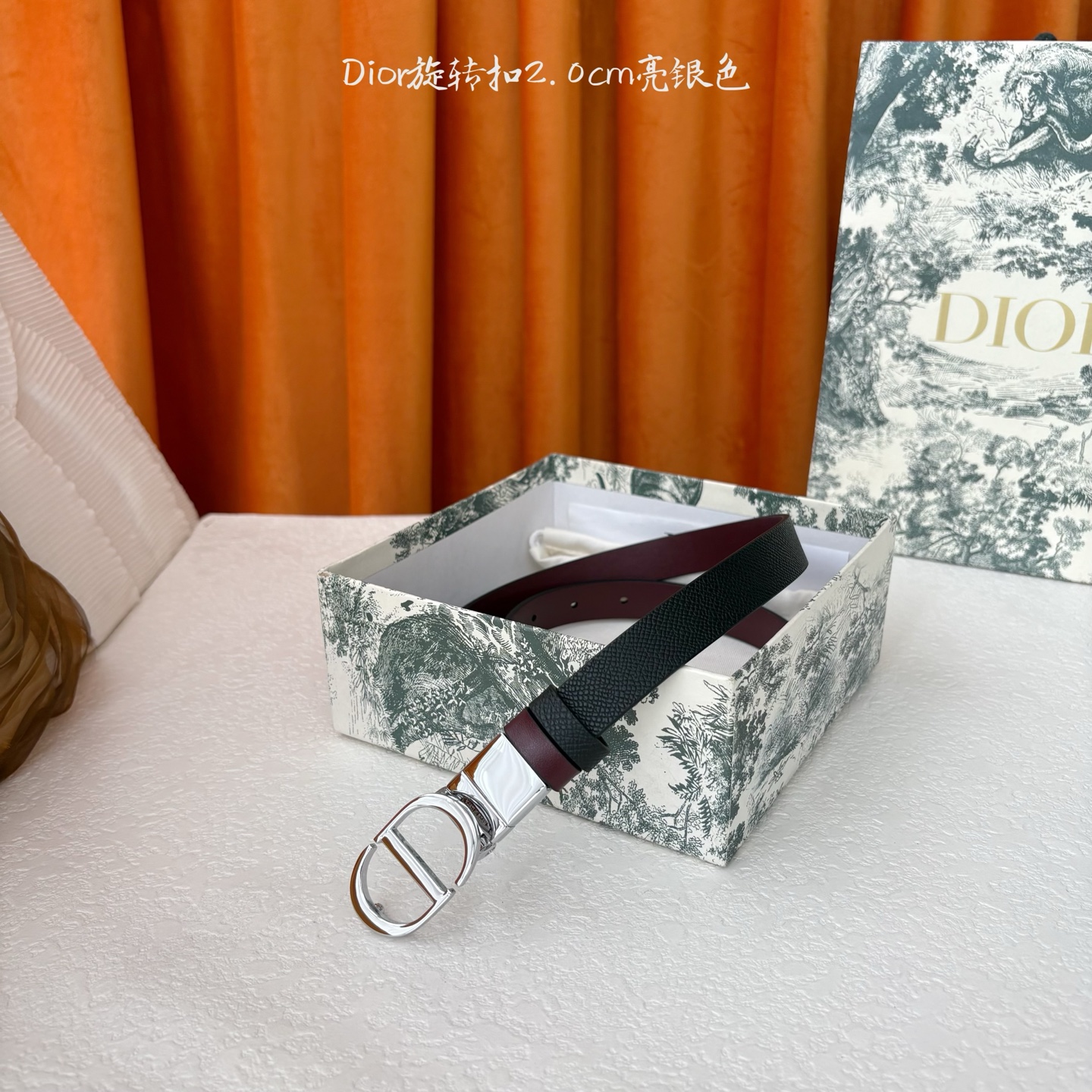 Dior新款腰带一面为黑色颗粒小牛皮，另一面为酒红色光滑小牛皮，缀以经典的亮面金色饰面金属CD扣环。此款