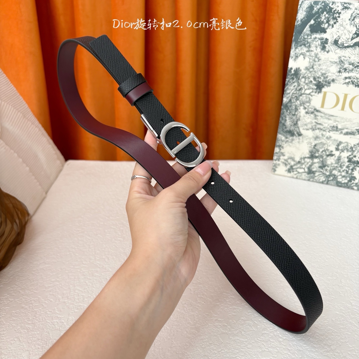 Dior新款腰带一面为黑色颗粒小牛皮,另一面为酒红色光滑小牛皮,缀以经典的亮面金色饰面金属CD扣环。此款