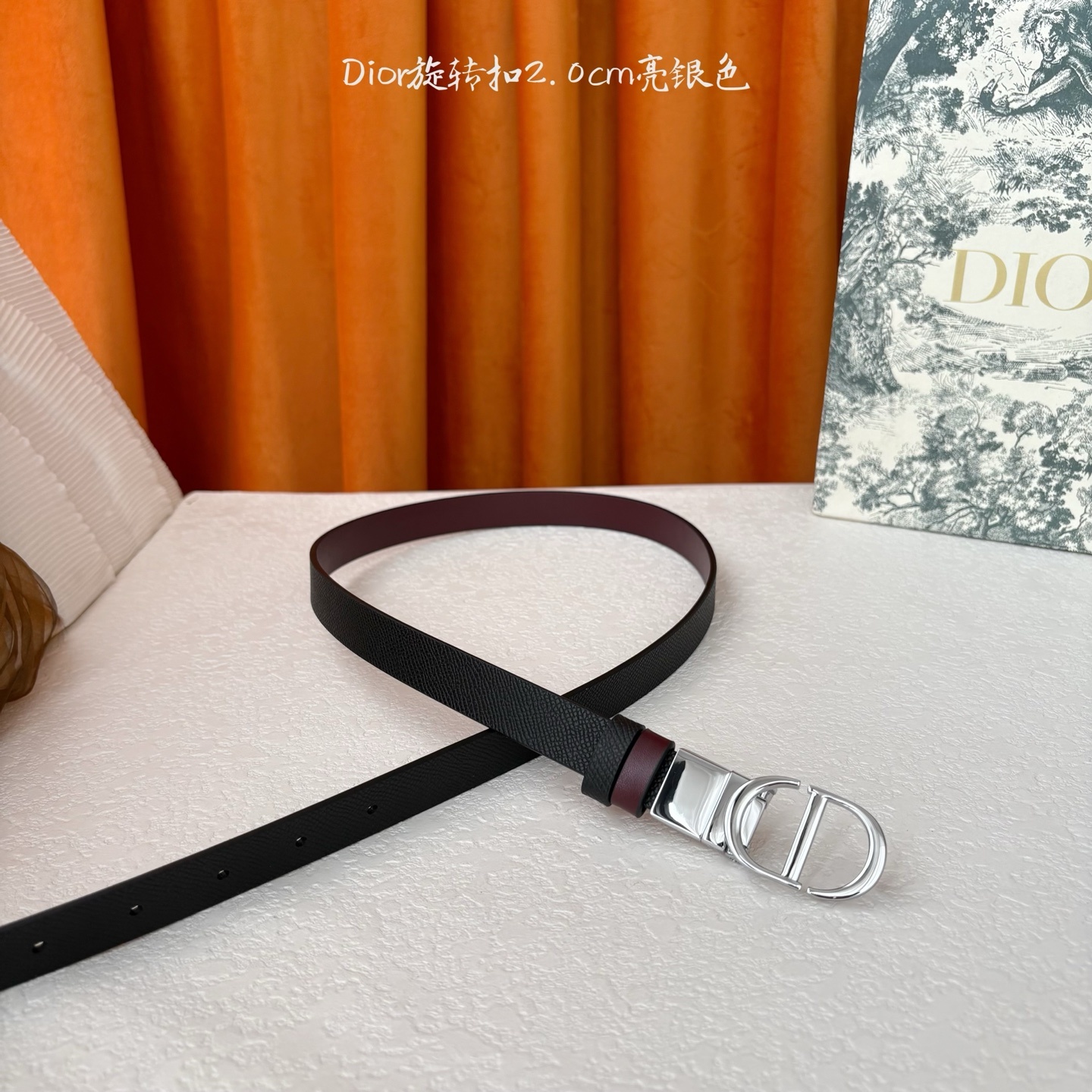 Dior新款腰带一面为黑色颗粒小牛皮,另一面为酒红色光滑小牛皮,缀以经典的亮面金色饰面金属CD扣环。此款