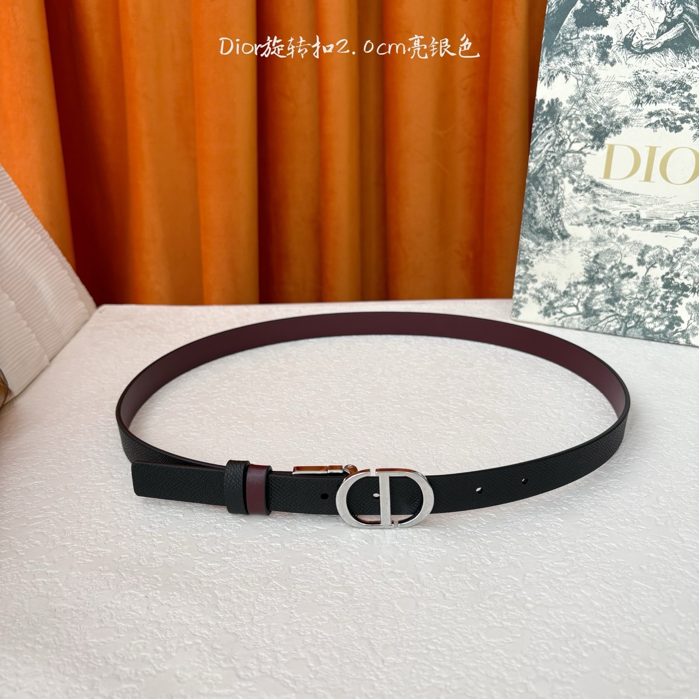 Dior新款腰带一面为黑色颗粒小牛皮,另一面为酒红色光滑小牛皮,缀以经典的亮面金色饰面金属CD扣环。此款