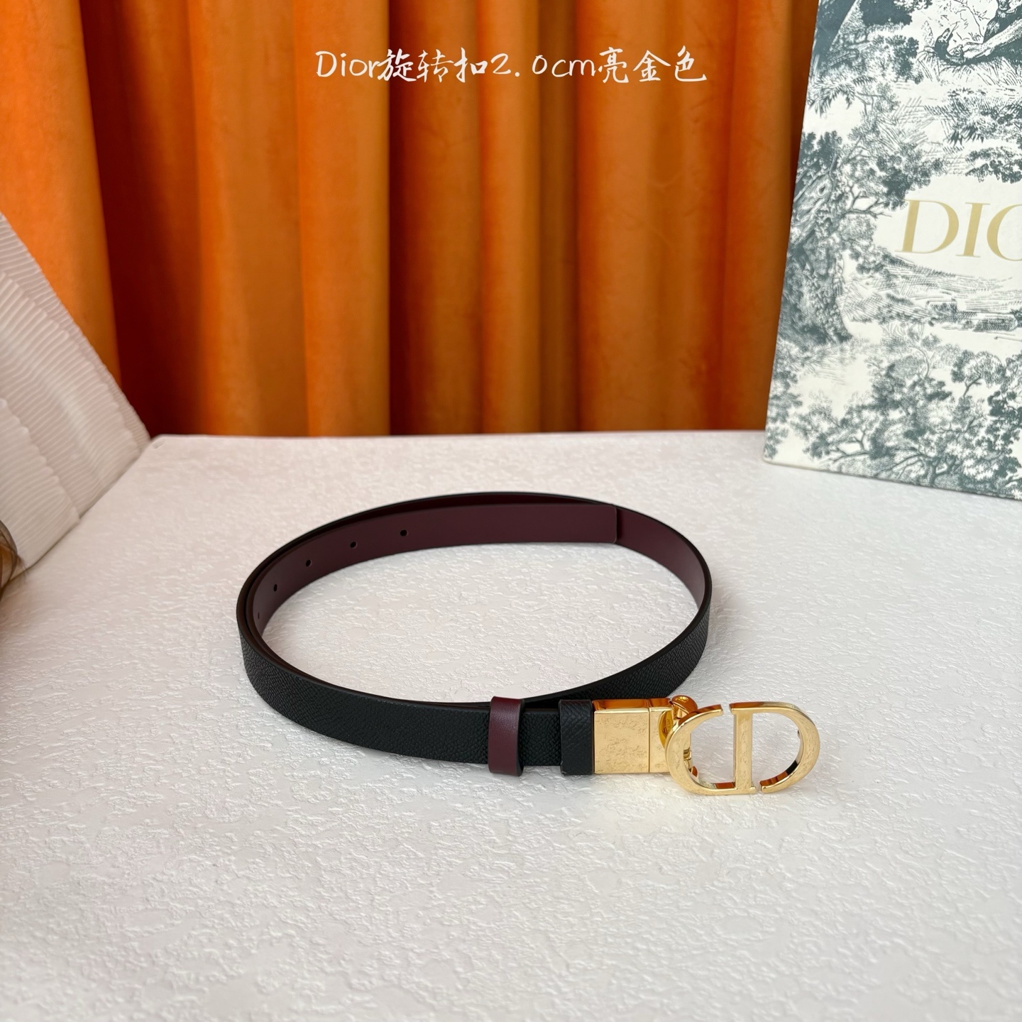 Dior新款腰带一面为黑色颗粒小牛皮,另一面为酒红色光滑小牛皮,缀以经典的亮面金色饰面金属CD扣环。此款