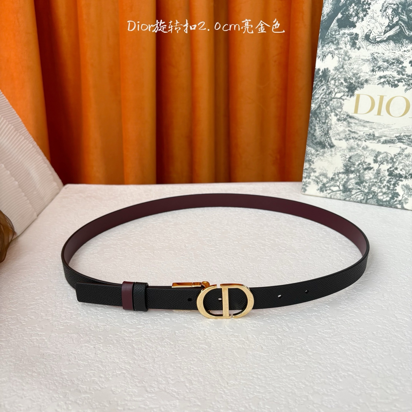 Dior新款腰带一面为黑色颗粒小牛皮,另一面为酒红色光滑小牛皮,缀以经典的亮面金色饰面金属CD扣环。此款