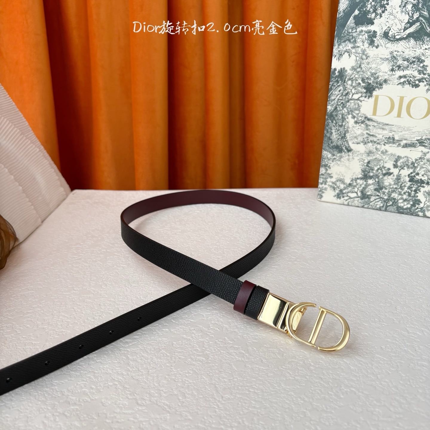 Dior新款腰带一面为黑色颗粒小牛皮,另一面为酒红色光滑小牛皮,缀以经典的亮面金色饰面金属CD扣环。此款