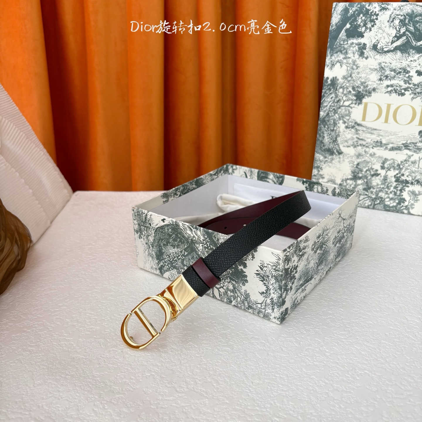 Dior新款腰带一面为黑色颗粒小牛皮，另一面为酒红色光滑小牛皮，缀以经典的亮面金色饰面金属CD扣环。此款