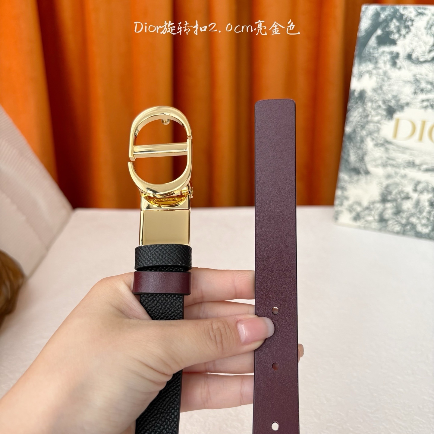 Dior新款腰带一面为黑色颗粒小牛皮,另一面为酒红色光滑小牛皮,缀以经典的亮面金色饰面金属CD扣环。此款
