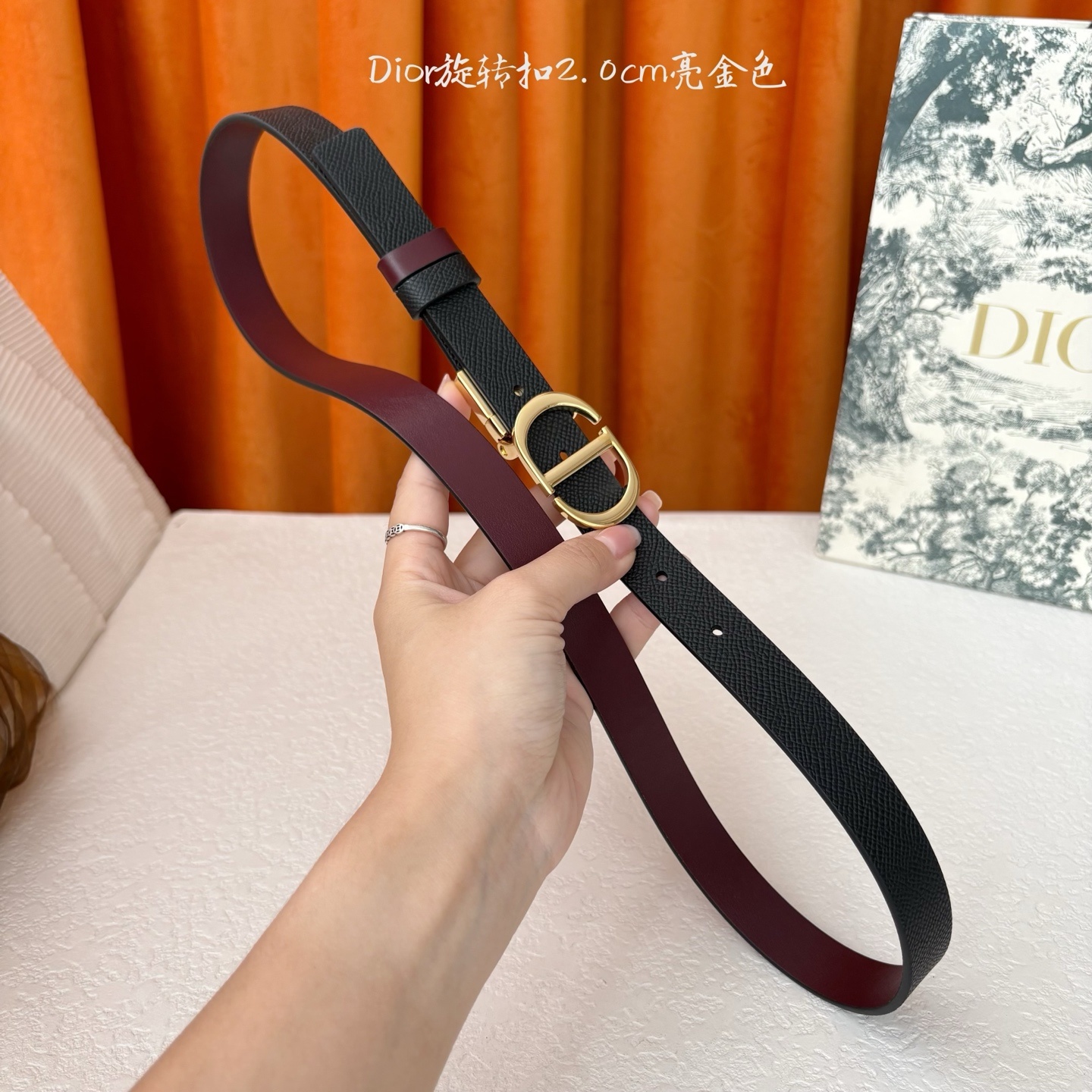 Dior新款腰带一面为黑色颗粒小牛皮,另一面为酒红色光滑小牛皮,缀以经典的亮面金色饰面金属CD扣环。此款