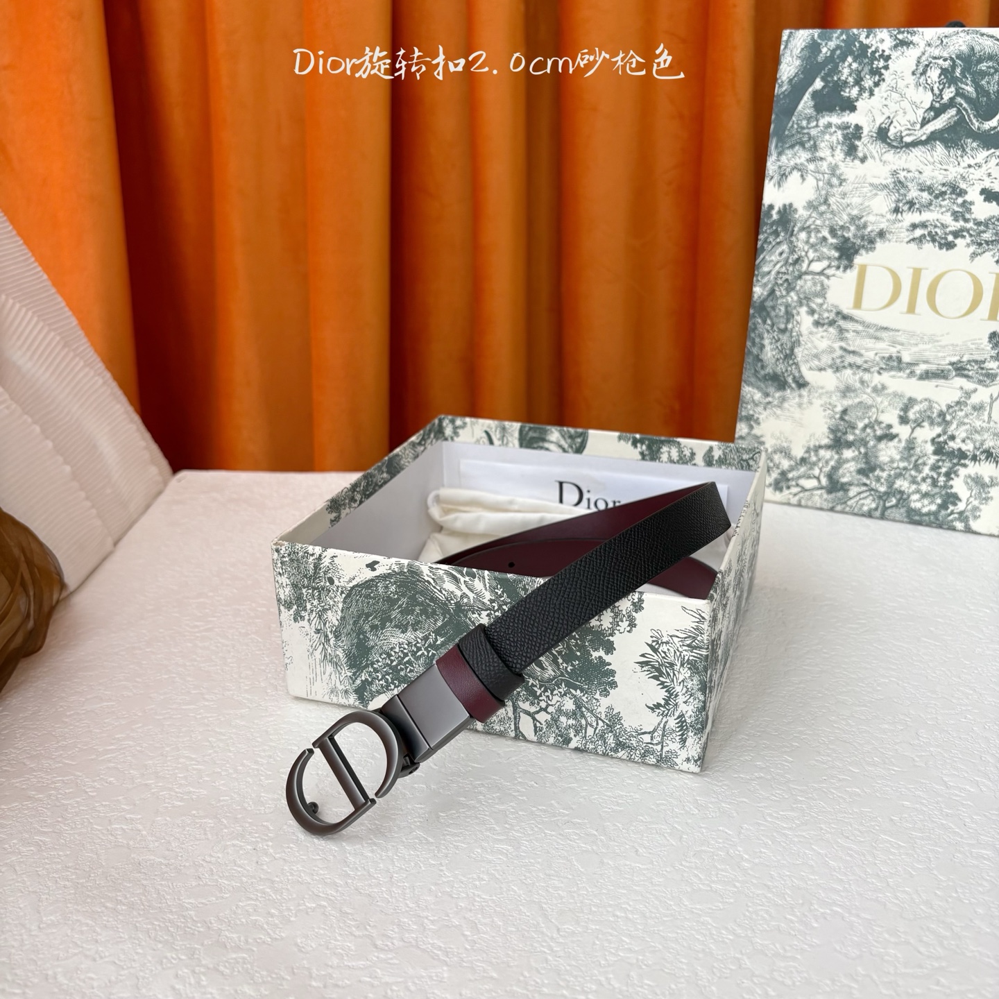 Dior新款腰带一面为黑色颗粒小牛皮，另一面为酒红色光滑小牛皮，缀以经典的亮面金色饰面金属CD扣环。此款