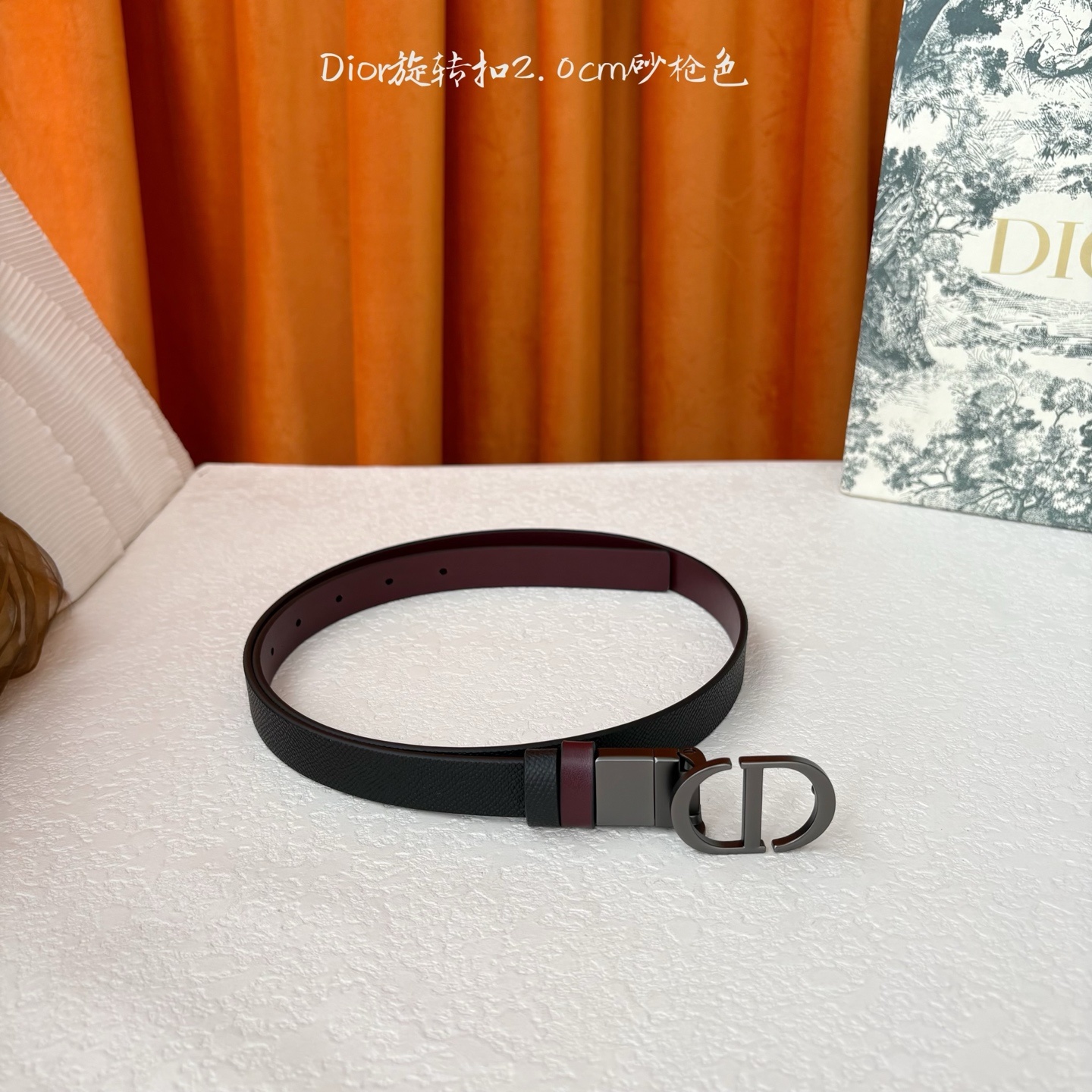 Dior新款腰带一面为黑色颗粒小牛皮,另一面为酒红色光滑小牛皮,缀以经典的亮面金色饰面金属CD扣环。此款