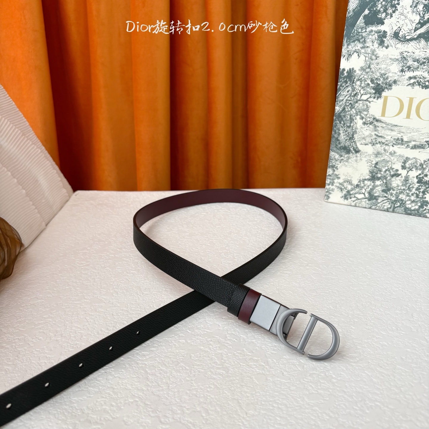 Dior新款腰带一面为黑色颗粒小牛皮,另一面为酒红色光滑小牛皮,缀以经典的亮面金色饰面金属CD扣环。此款