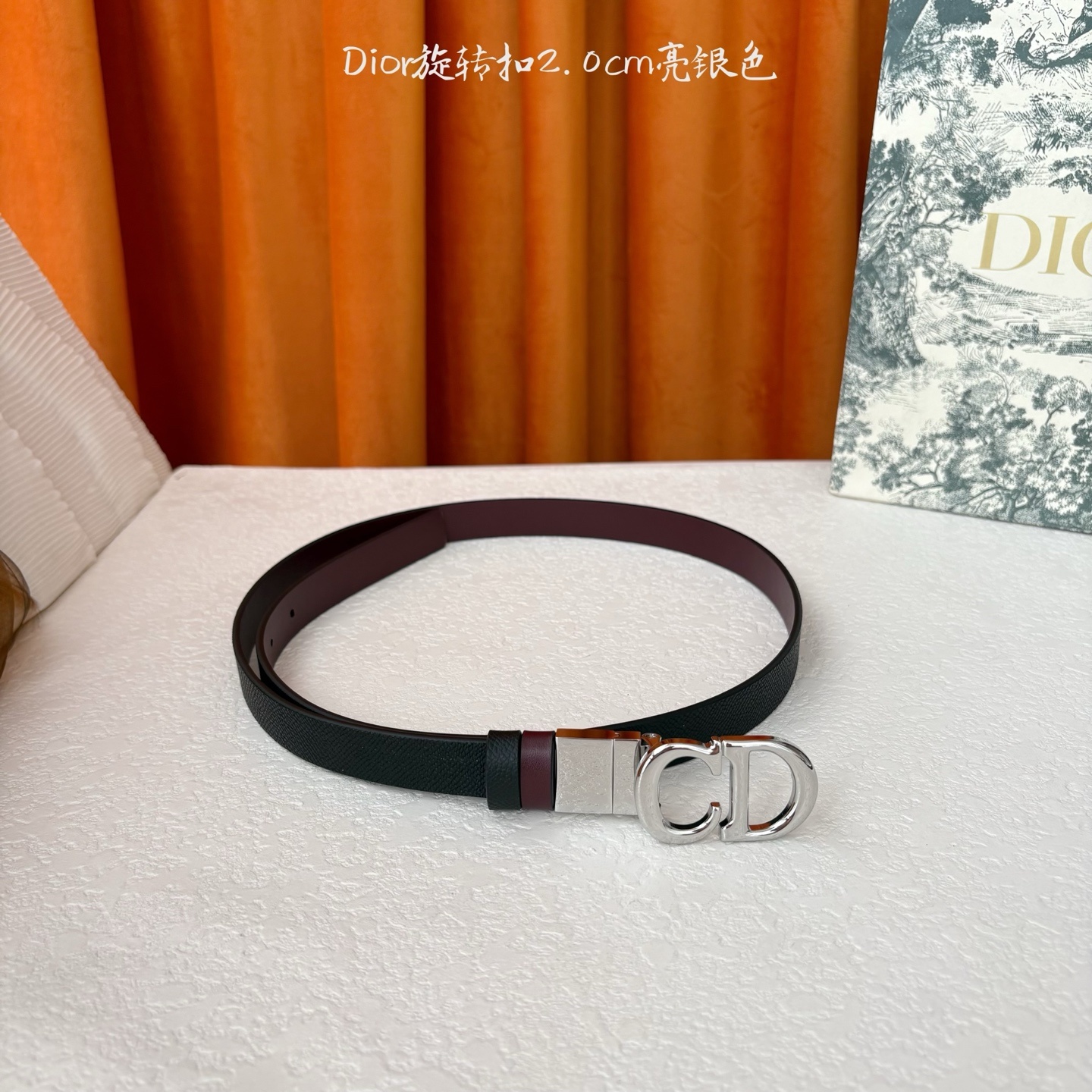 Dior新款腰带一面为黑色颗粒小牛皮,另一面为酒红色光滑小牛皮,缀以经典的亮面金色饰面金属CD扣环。此款