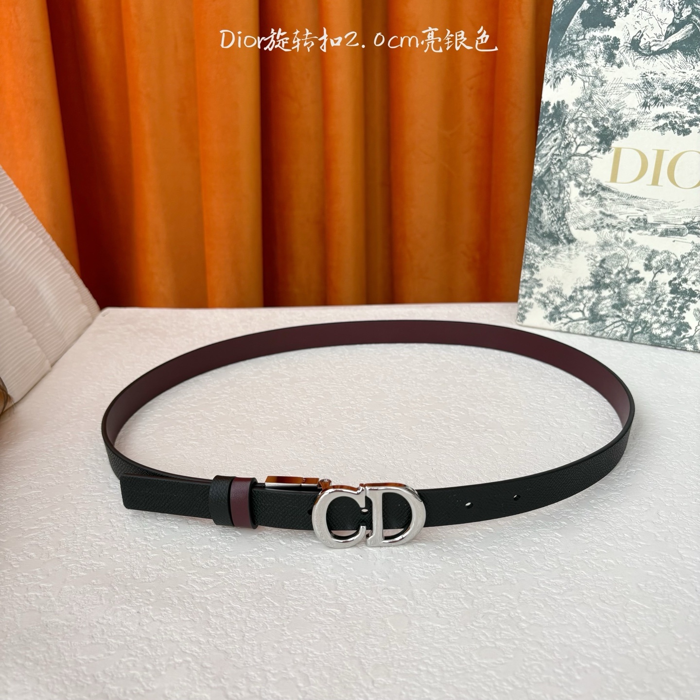 Dior新款腰带一面为黑色颗粒小牛皮,另一面为酒红色光滑小牛皮,缀以经典的亮面金色饰面金属CD扣环。此款