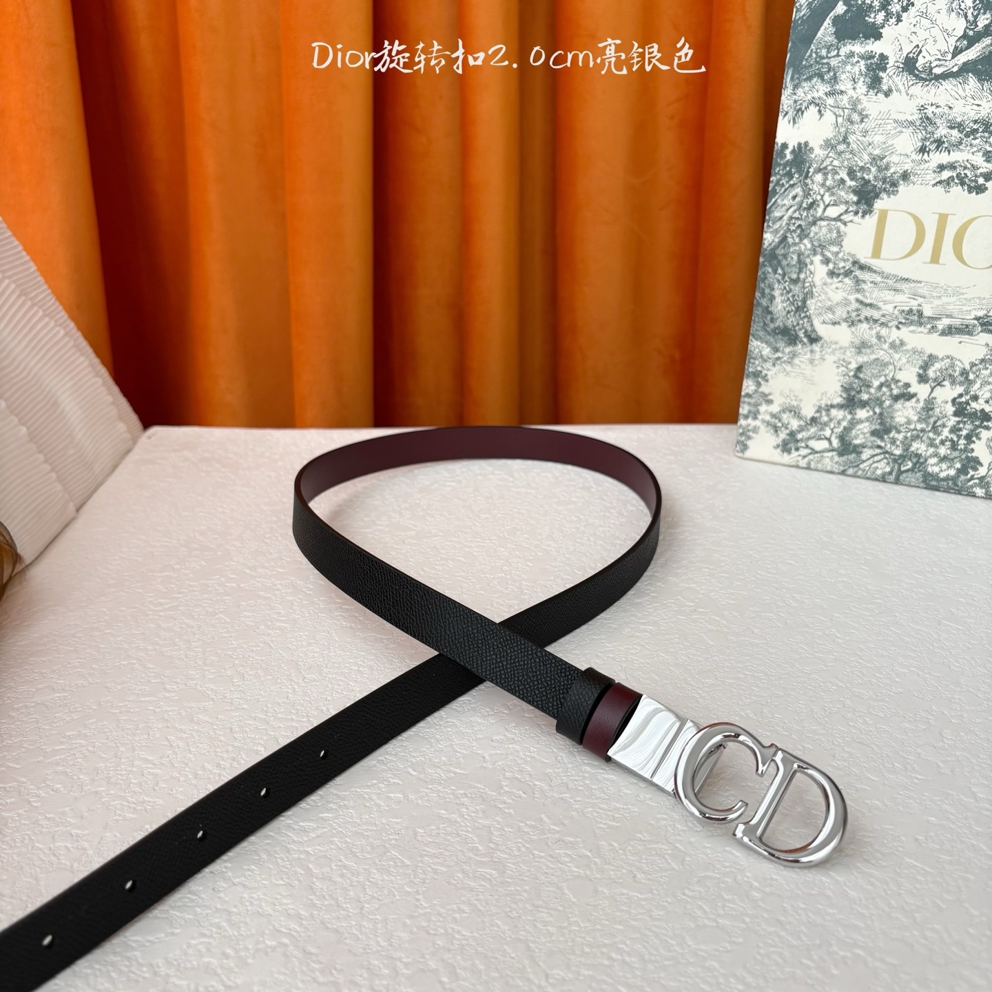 Dior新款腰带一面为黑色颗粒小牛皮,另一面为酒红色光滑小牛皮,缀以经典的亮面金色饰面金属CD扣环。此款