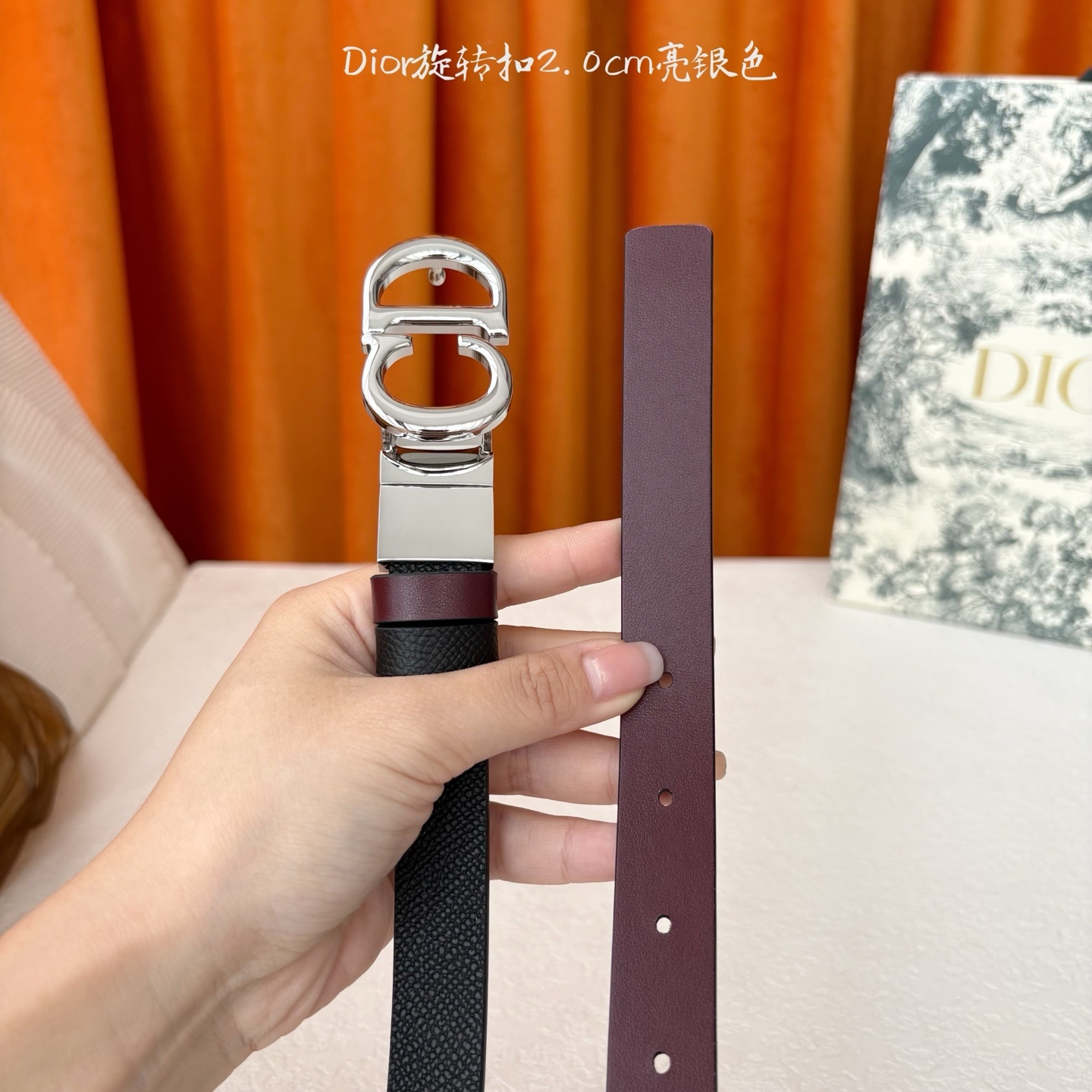 Dior新款腰带一面为黑色颗粒小牛皮,另一面为酒红色光滑小牛皮,缀以经典的亮面金色饰面金属CD扣环。此款