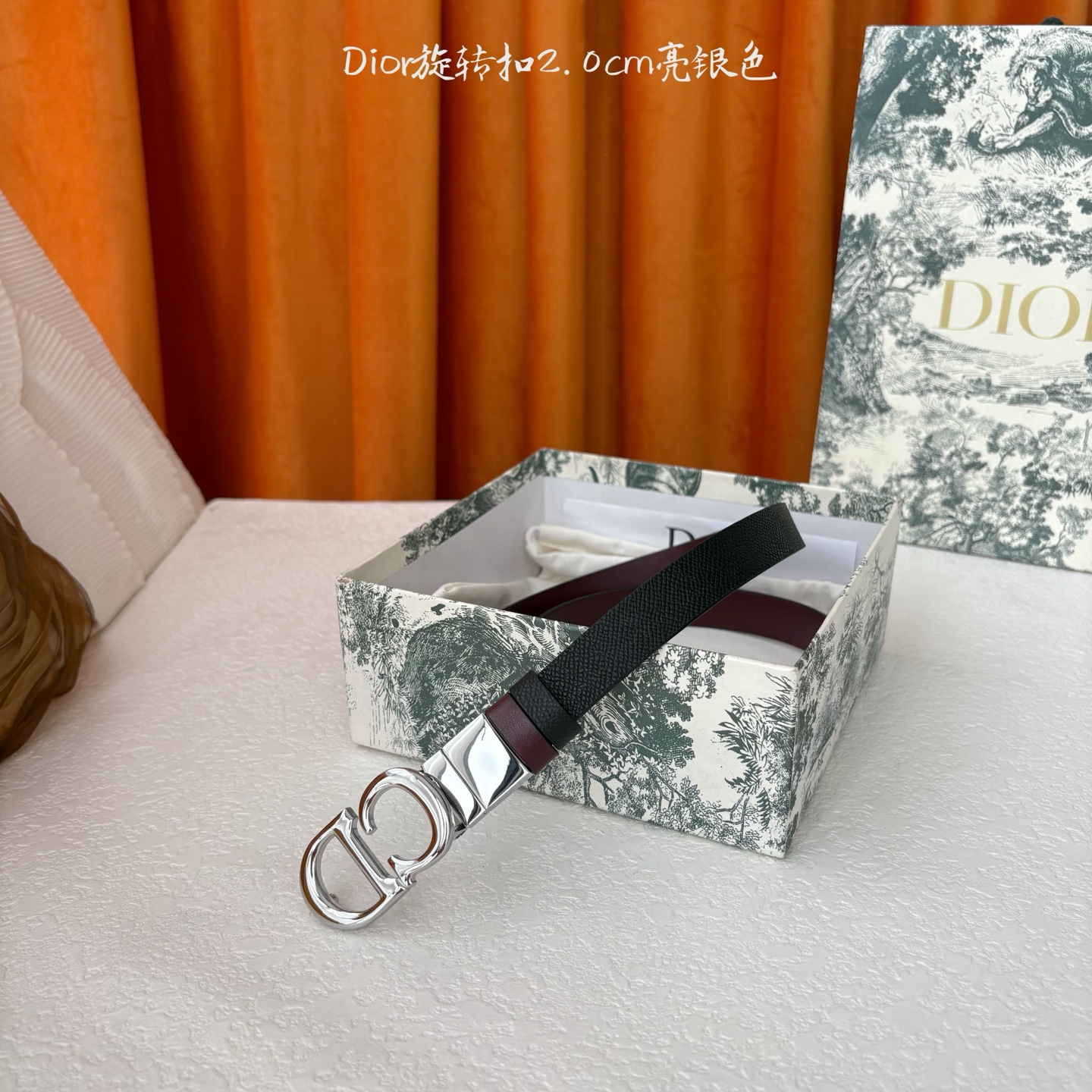 Dior新款腰带一面为黑色颗粒小牛皮，另一面为酒红色光滑小牛皮，缀以经典的亮面金色饰面金属CD扣环。此款