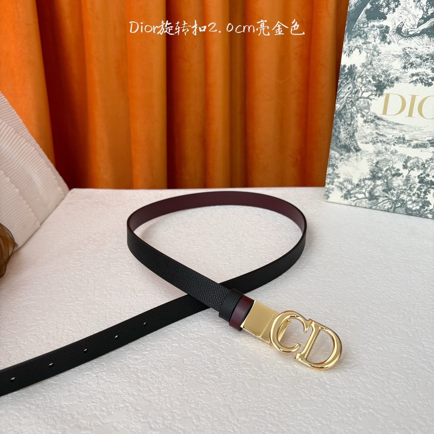 Dior新款腰带一面为黑色颗粒小牛皮,另一面为酒红色光滑小牛皮,缀以经典的亮面金色饰面金属CD扣环。此款