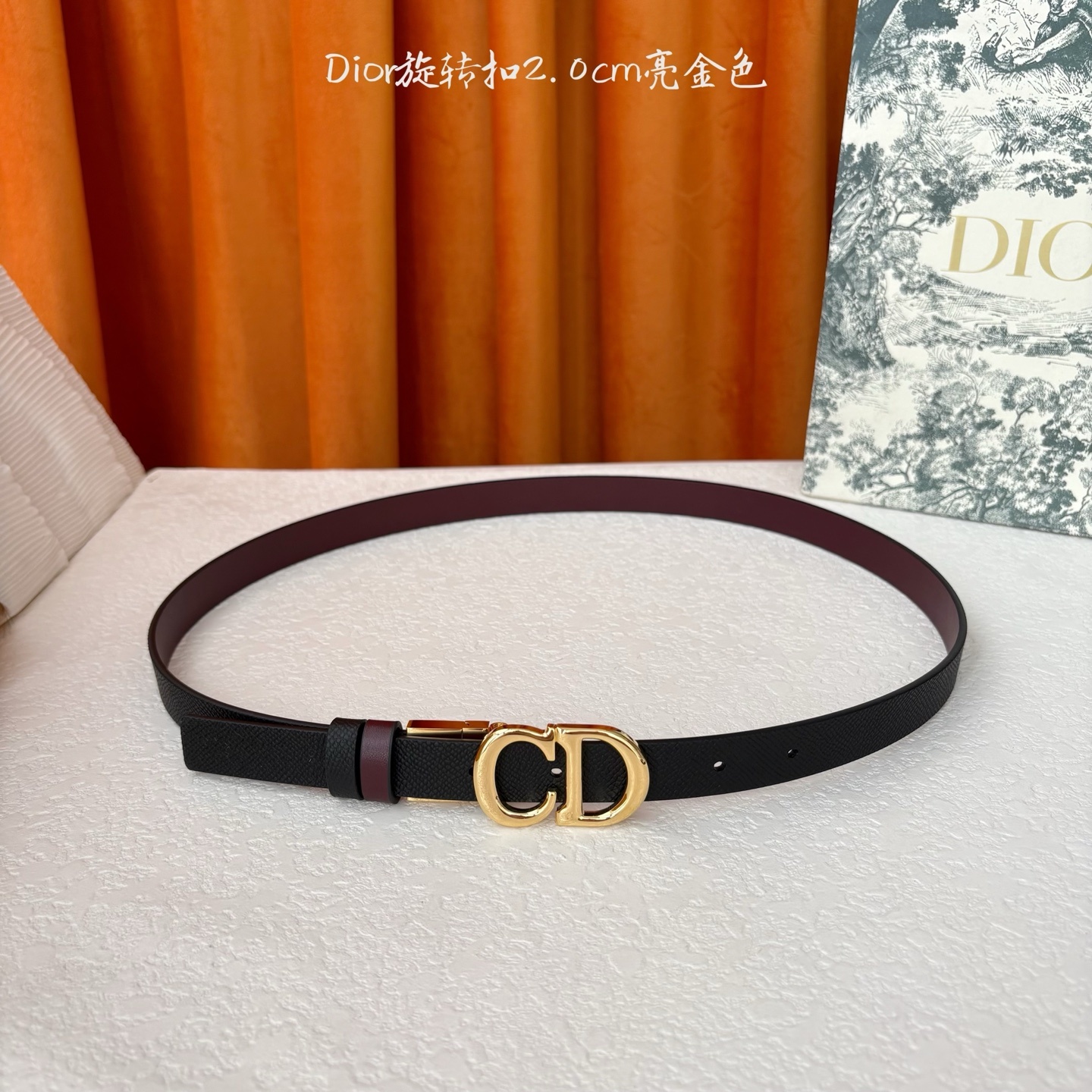 Dior新款腰带一面为黑色颗粒小牛皮,另一面为酒红色光滑小牛皮,缀以经典的亮面金色饰面金属CD扣环。此款
