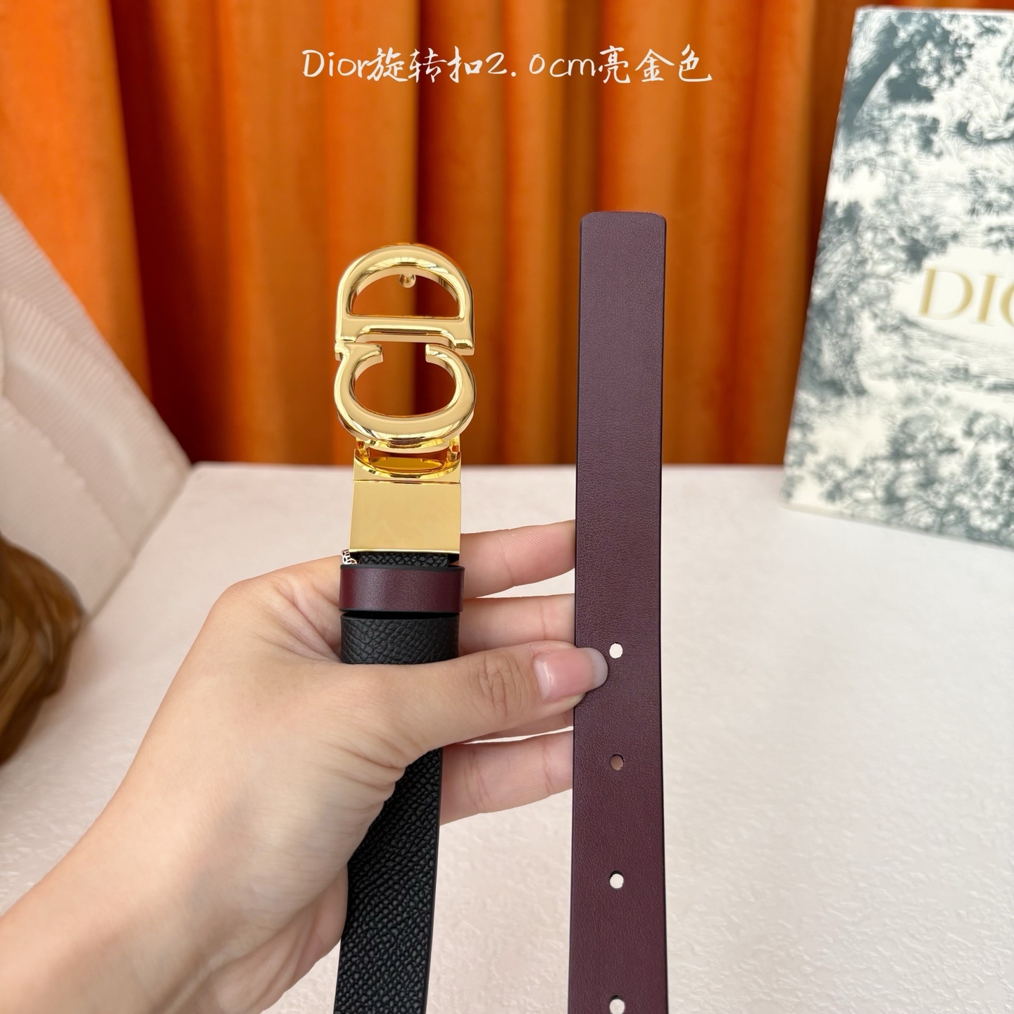 Dior新款腰带一面为黑色颗粒小牛皮,另一面为酒红色光滑小牛皮,缀以经典的亮面金色饰面金属CD扣环。此款
