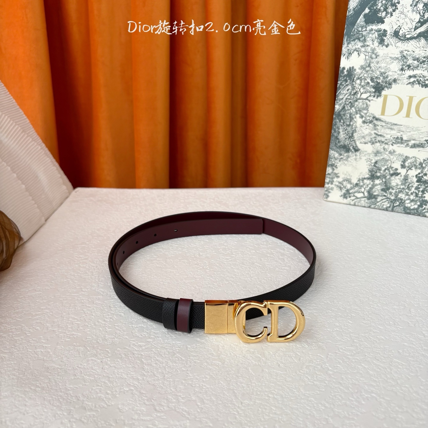 Dior新款腰带一面为黑色颗粒小牛皮,另一面为酒红色光滑小牛皮,缀以经典的亮面金色饰面金属CD扣环。此款