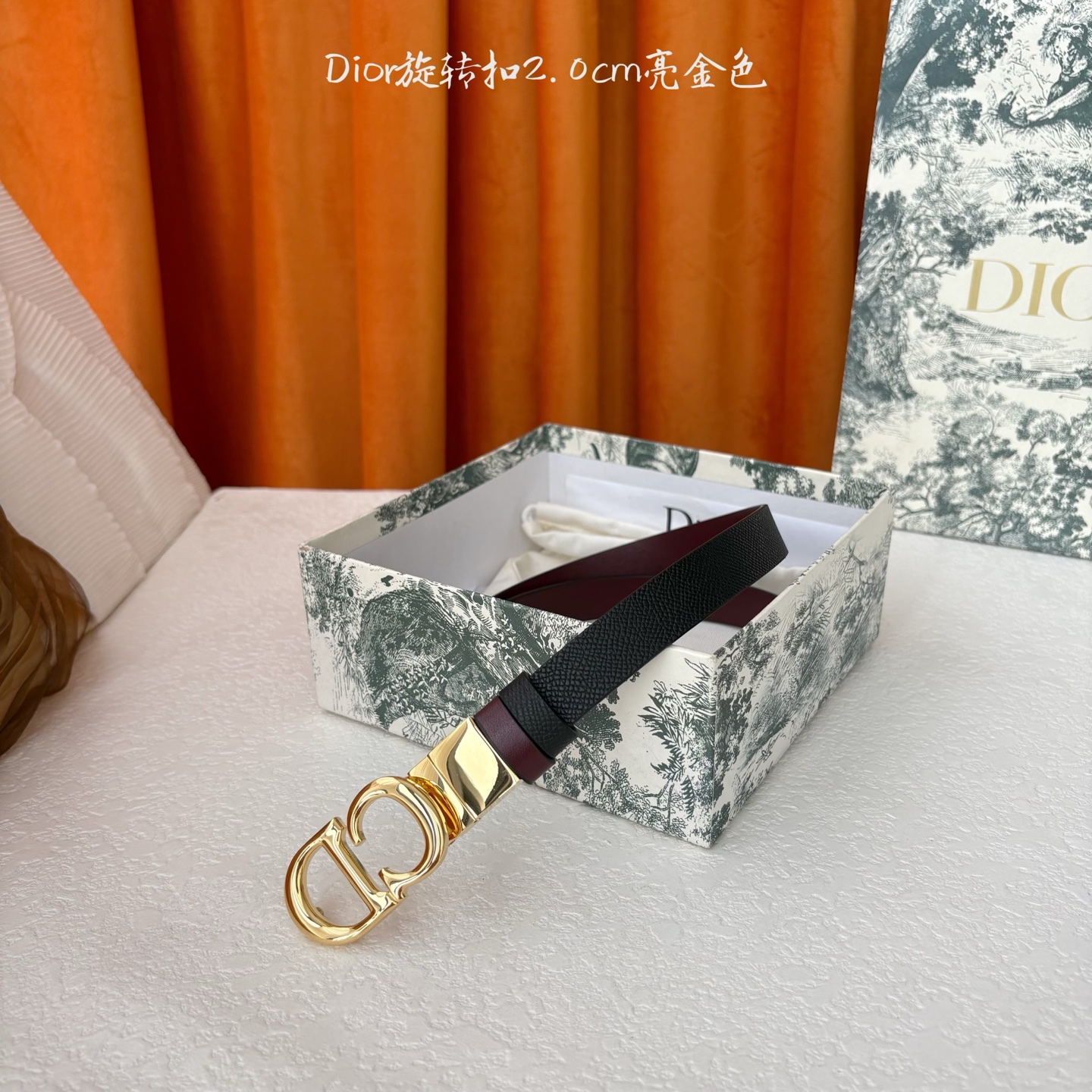 Dior新款腰带一面为黑色颗粒小牛皮，另一面为酒红色光滑小牛皮，缀以经典的亮面金色饰面金属CD扣环。此款