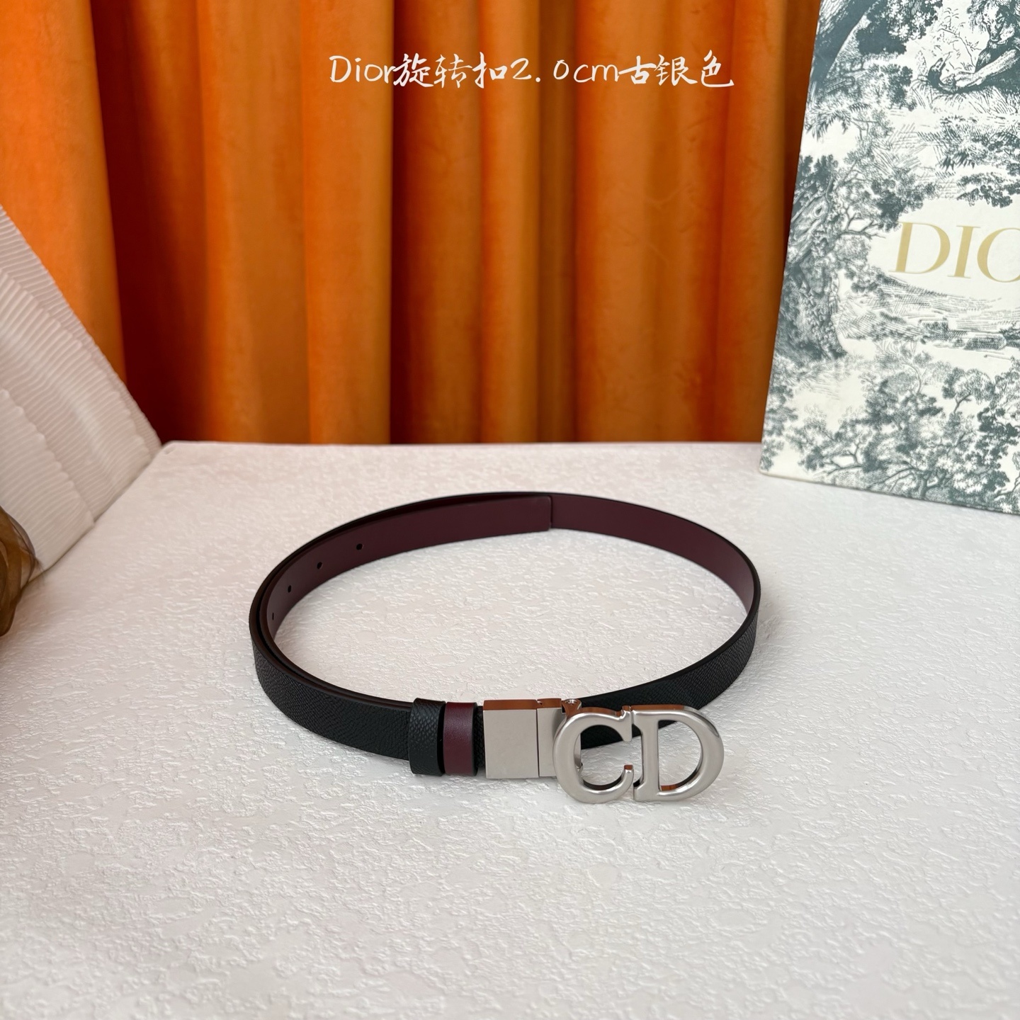 Dior新款腰带一面为黑色颗粒小牛皮,另一面为酒红色光滑小牛皮,缀以经典的亮面金色饰面金属CD扣环。此款