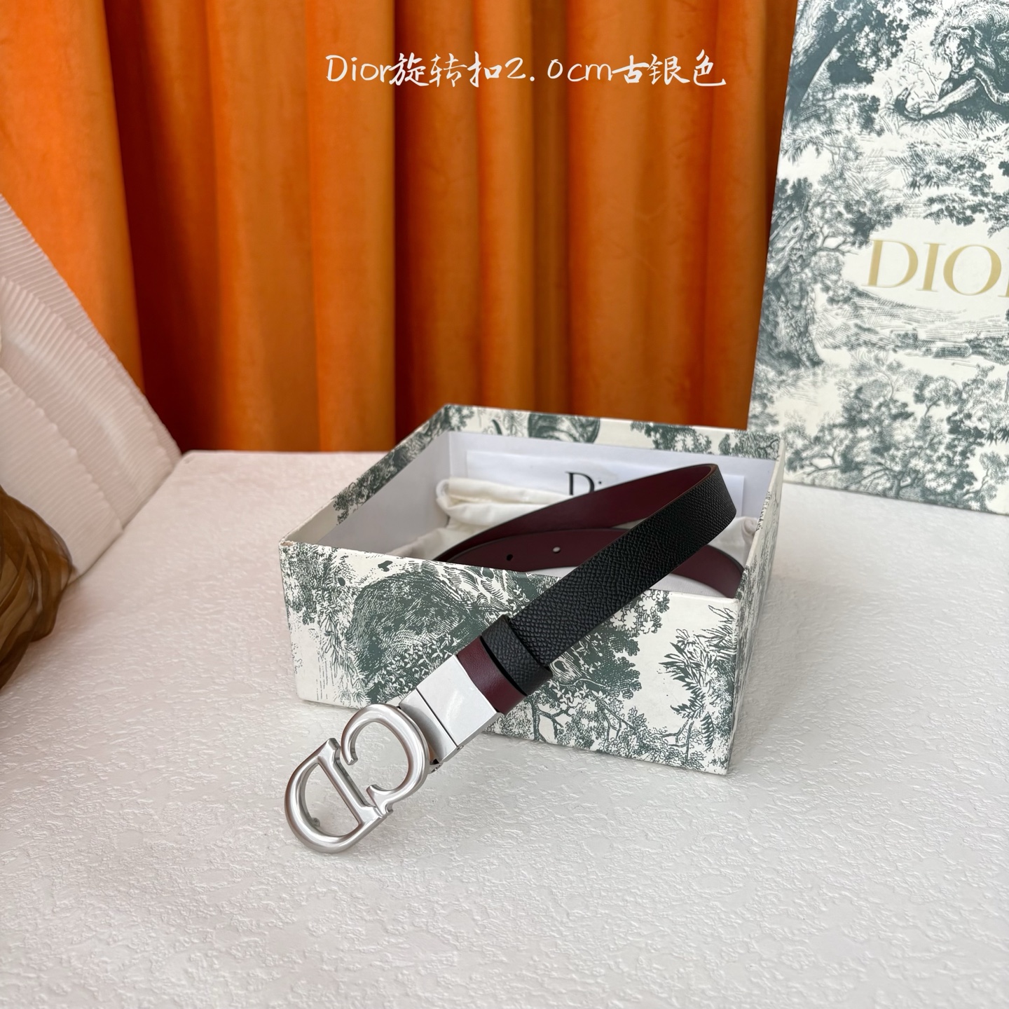 Dior新款腰带一面为黑色颗粒小牛皮，另一面为酒红色光滑小牛皮，缀以经典的亮面金色饰面金属CD扣环。此款