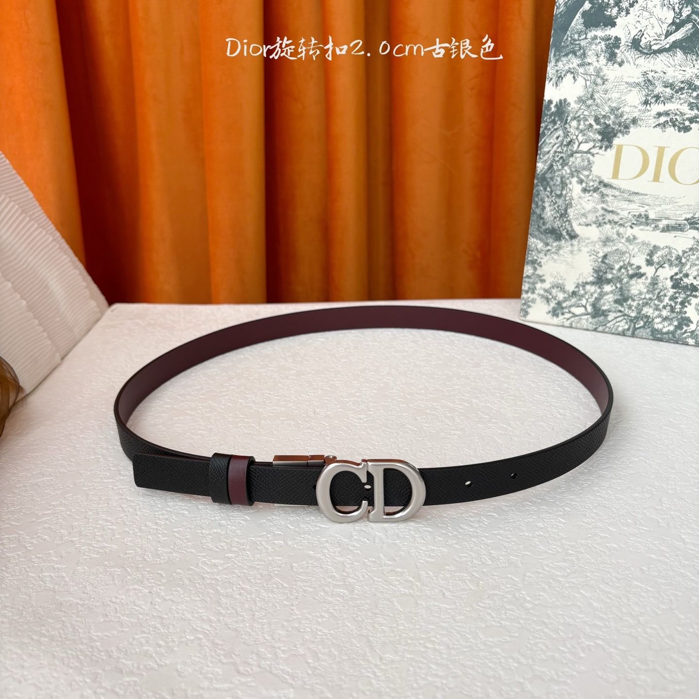 Dior新款腰带一面为黑色颗粒小牛皮,另一面为酒红色光滑小牛皮,缀以经典的亮面金色饰面金属CD扣环。此款
