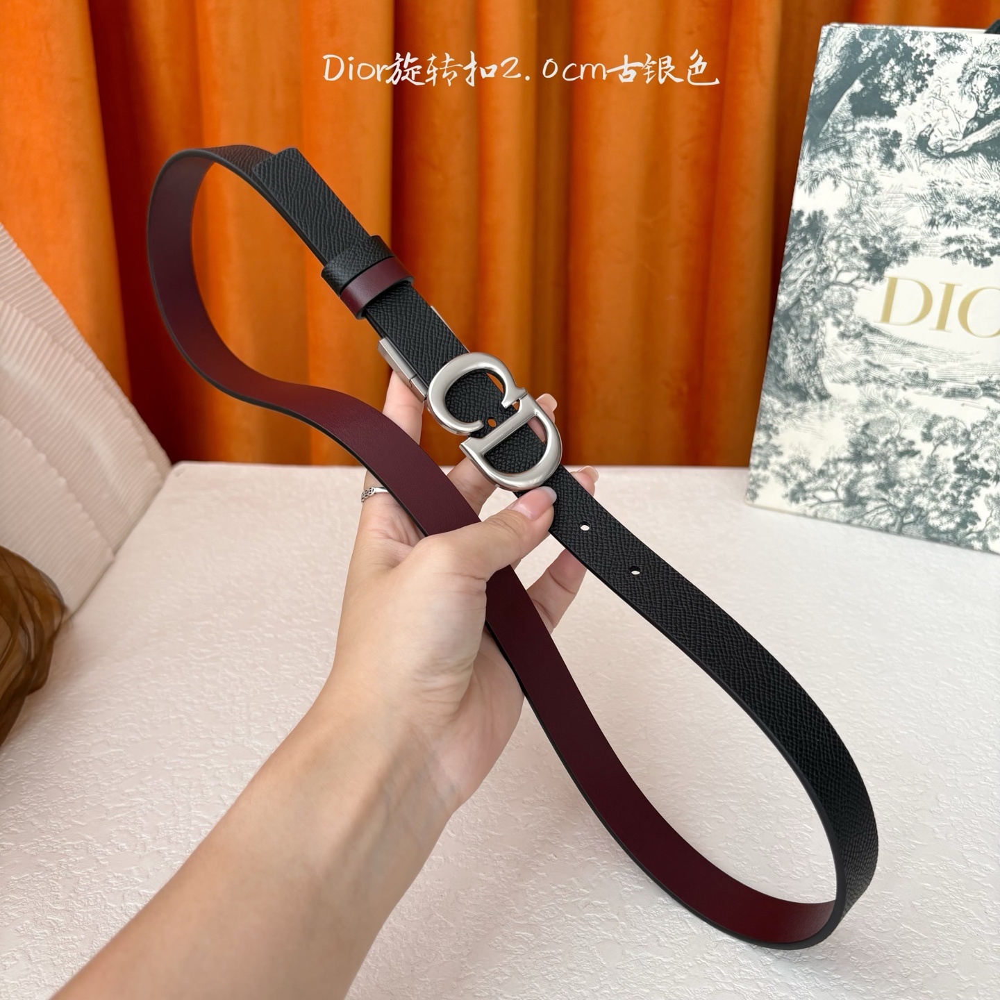 Dior新款腰带一面为黑色颗粒小牛皮,另一面为酒红色光滑小牛皮,缀以经典的亮面金色饰面金属CD扣环。此款