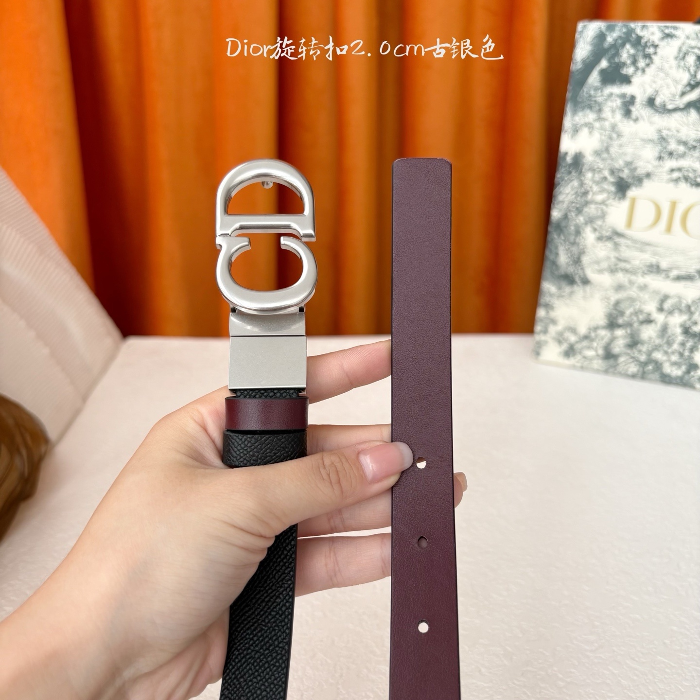 Dior新款腰带一面为黑色颗粒小牛皮,另一面为酒红色光滑小牛皮,缀以经典的亮面金色饰面金属CD扣环。此款