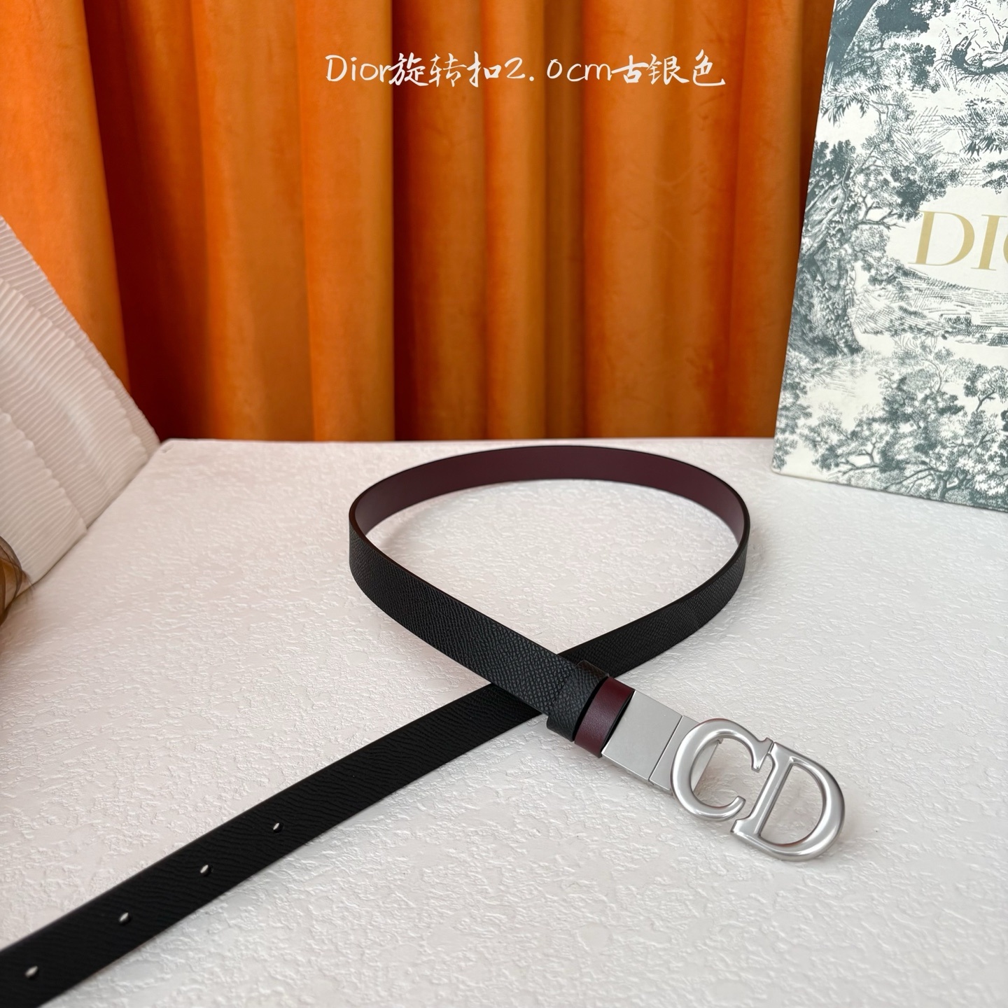 Dior新款腰带一面为黑色颗粒小牛皮,另一面为酒红色光滑小牛皮,缀以经典的亮面金色饰面金属CD扣环。此款