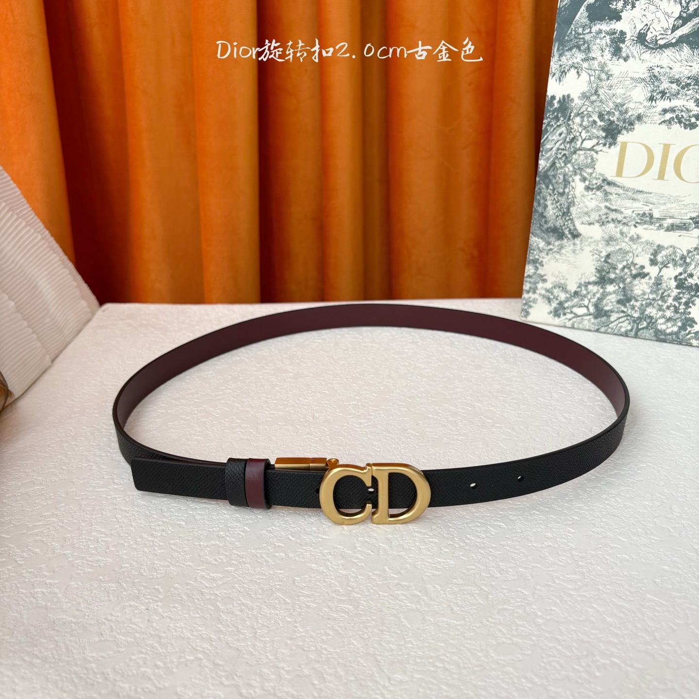 Dior新款腰带一面为黑色颗粒小牛皮,另一面为酒红色光滑小牛皮,缀以经典的亮面金色饰面金属CD扣环。此款