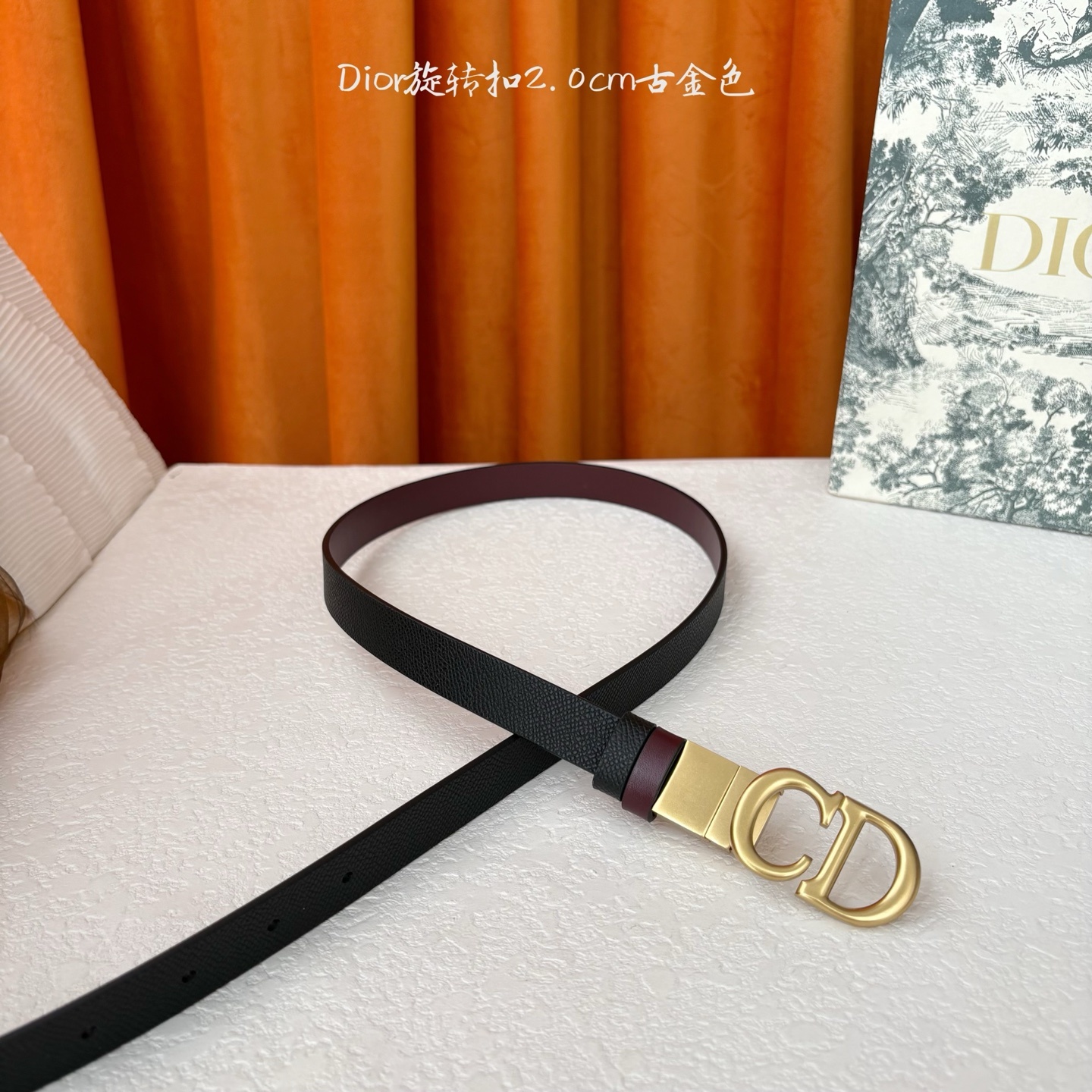 Dior新款腰带一面为黑色颗粒小牛皮,另一面为酒红色光滑小牛皮,缀以经典的亮面金色饰面金属CD扣环。此款