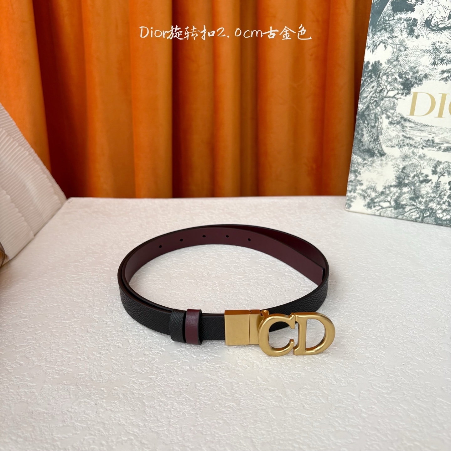 Dior新款腰带一面为黑色颗粒小牛皮,另一面为酒红色光滑小牛皮,缀以经典的亮面金色饰面金属CD扣环。此款