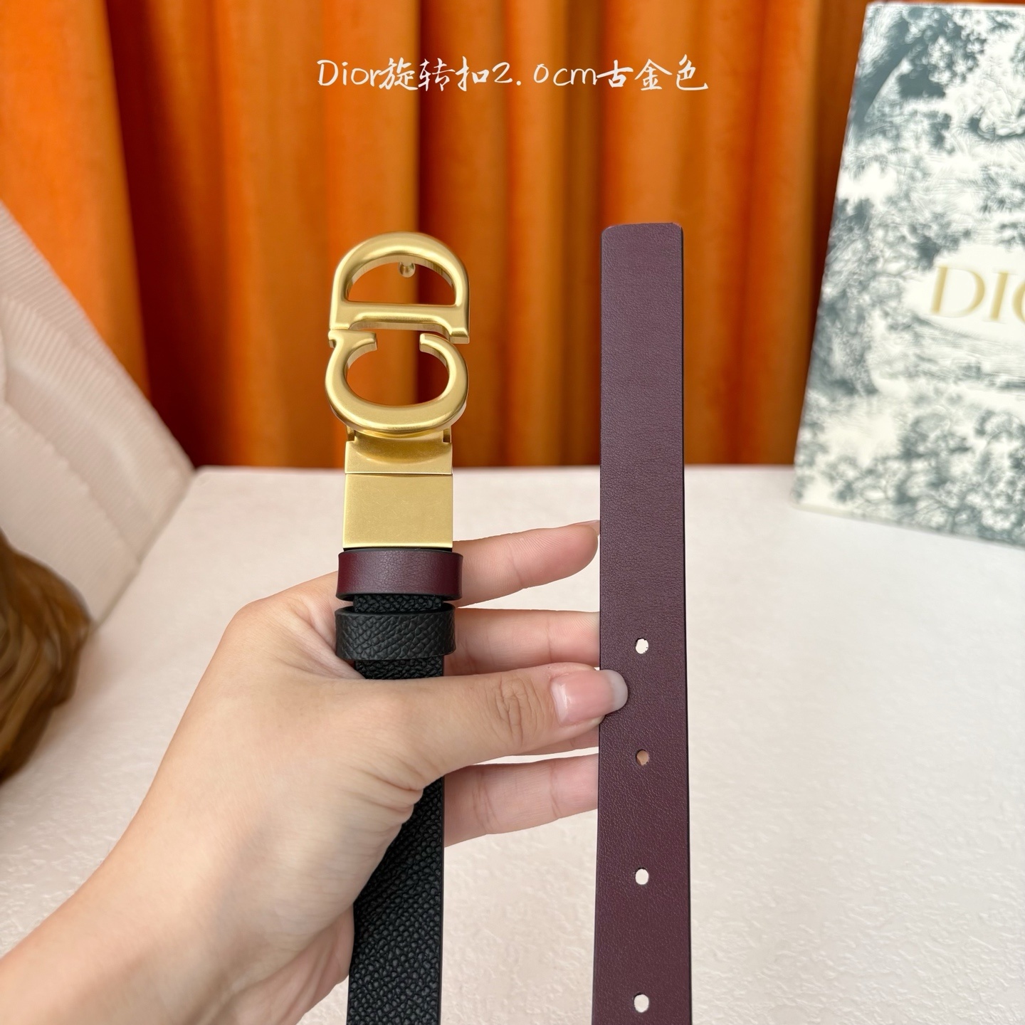Dior新款腰带一面为黑色颗粒小牛皮,另一面为酒红色光滑小牛皮,缀以经典的亮面金色饰面金属CD扣环。此款