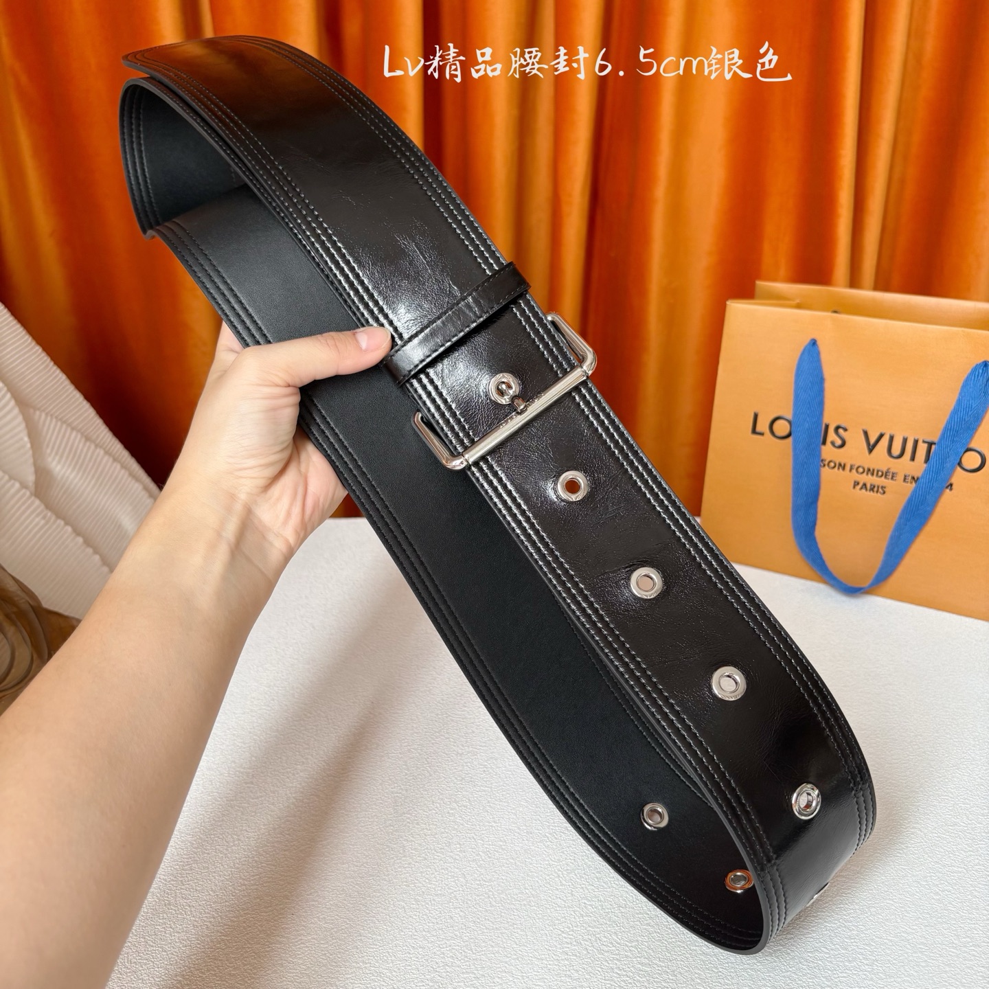 Lv Trench 65毫米腰带采用油蜡小牛皮制成，独一无二的腰带以众多孔眼和坚固的金色搭扣向著名外套的