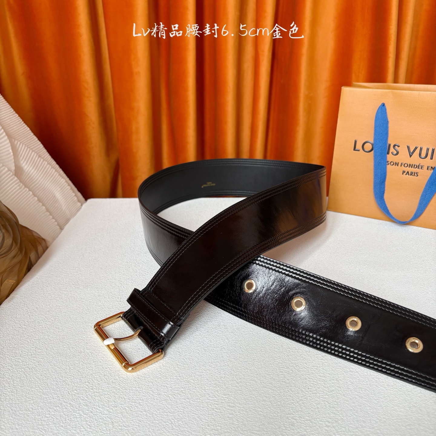 Lv Trench 65毫米腰带采用油蜡小牛皮制成，独一无二的腰带以众多孔眼和坚固的金色搭扣向著名外套的