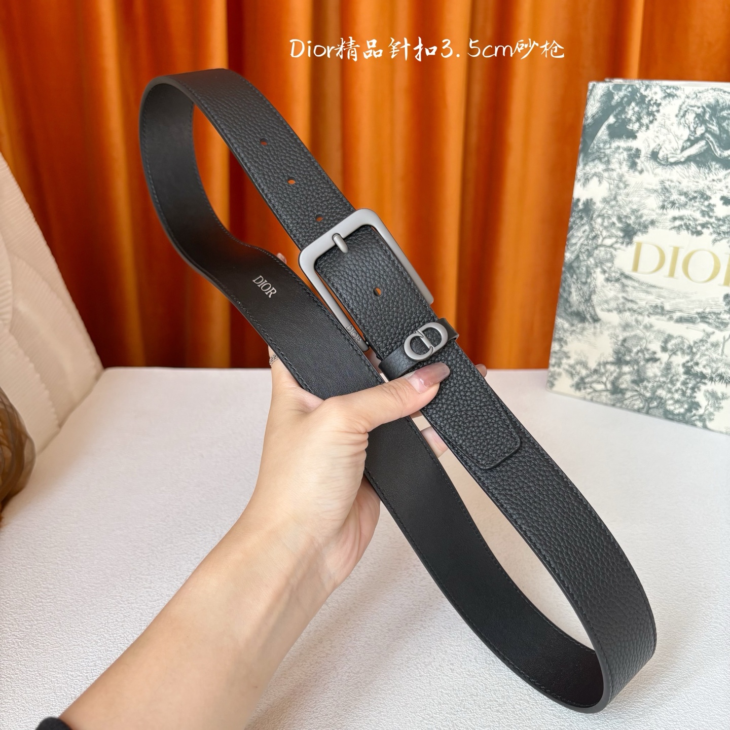 Dior这款腰带采用黑色粒面牛皮革精心制作，饰以镌刻有 Dior 的针扣和金属 CD Icon 标志腰带