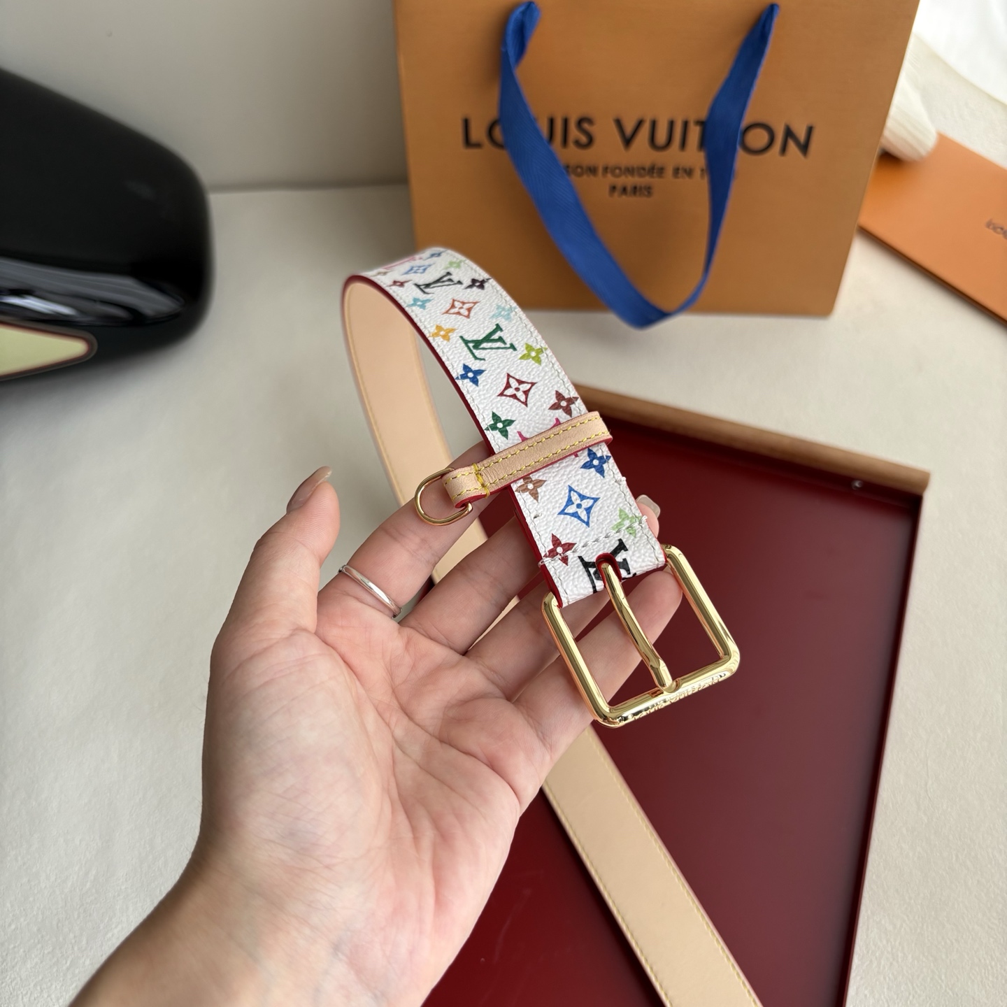 Lv3.0mm白彩双面腰带，以展现艺术家对品牌经典图案的灵动演绎，搭配针式搭扣和方便悬挂钥匙或装饰的D形