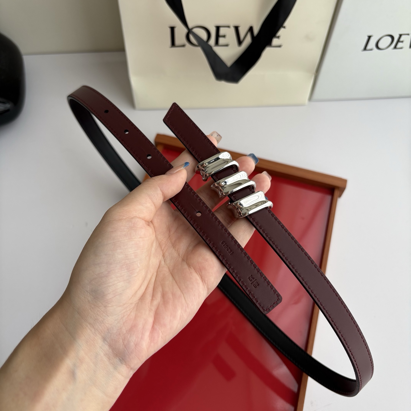 Loewe光滑牛皮革Coil双面腰带，饰有灵感源自品牌典藏的盘绕配件。Anchor腰带扣，宽1.5cm，五孔调节。黑色/