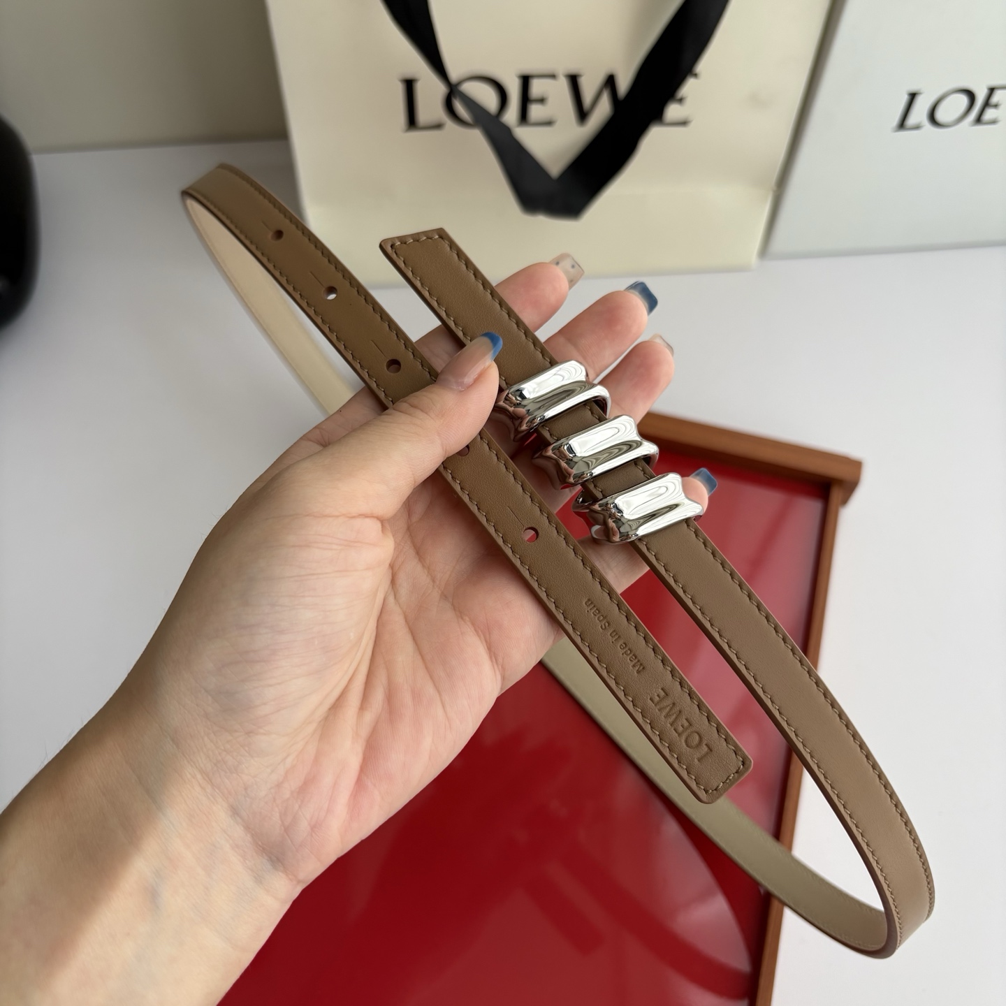 Loewe光滑牛皮革Coil双面腰带，饰有灵感源自品牌典藏的盘绕配件。Anchor腰带扣，宽1.5cm，五孔调节。摩卡色